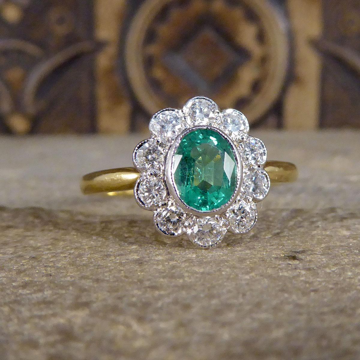 This contemporary ring holds a 0.65ct mesmerisingly bright green Emerald in the centre of the ring and surrounded by 10 Modern Brilliant cut bright and clear Diamonds making a cluster. Complimenting the gemstones is an 18ct White Gold rub over