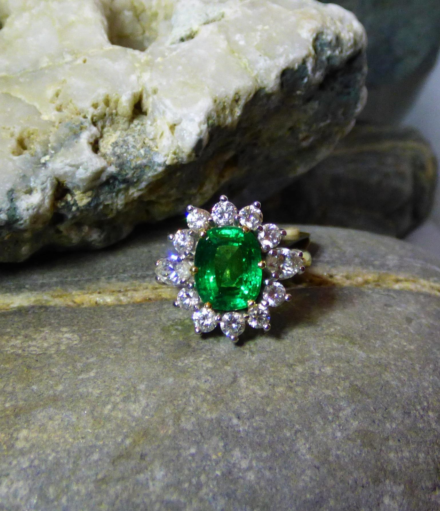 An exquisitely clean and bright  2.85ct. oval Emerald. This top grade colour of Emerald is an untreated natural stone.  A few minor inclusions are visible. The ring is also set with 10 round Diamonds (1.0ct.) and two marquise cut Diamonds (.66ct.).