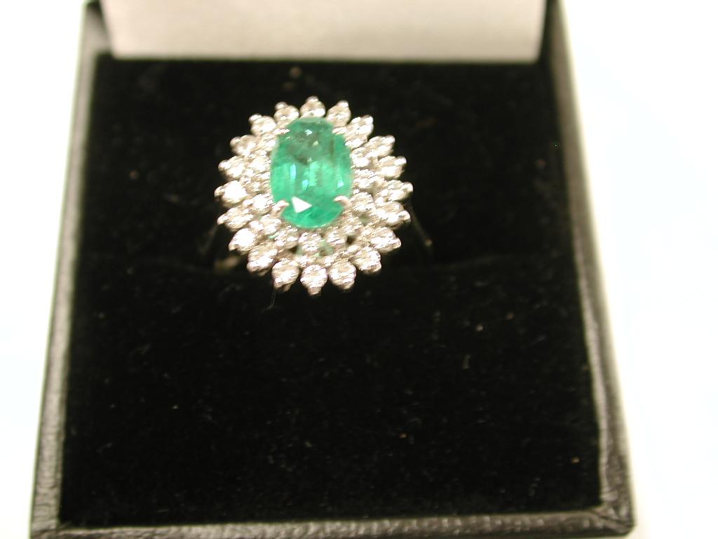 Emerald and Diamond Cluster Ring mounted in 18ct White Gold,London, 1979
This exquisite ring has never been worn and was ex- stock from a Hatton Garden Manufacturer.
The emerald size is 1.20 carats and the surround of diamonds weigh 40 points.