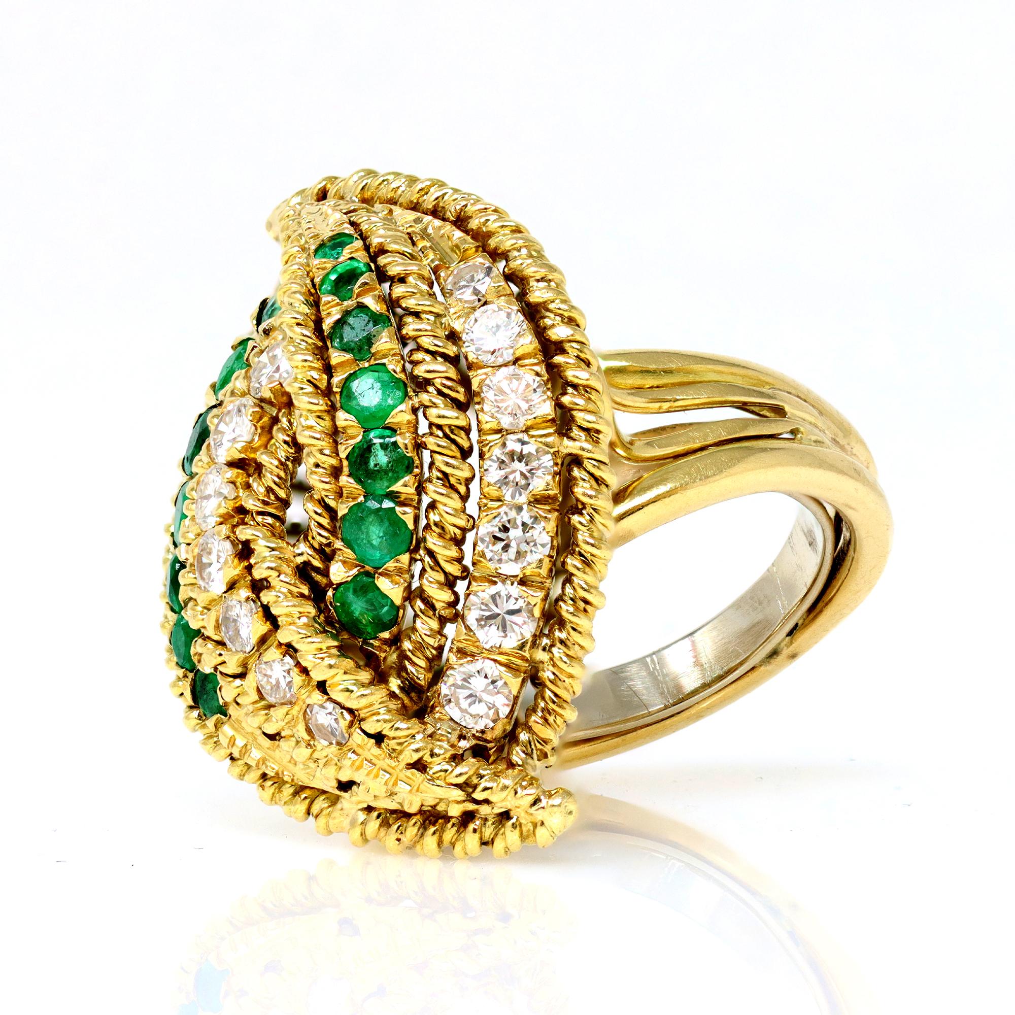 A cocktail ring Ca. 1970 featuring a bypass design with lines of diamonds and emeralds. The ring is hand executed in 18 karat yellow gold. The diamonds are full cut round shape with an estimated weight of 0.60 carats, GH color and VS-SI clarity. The