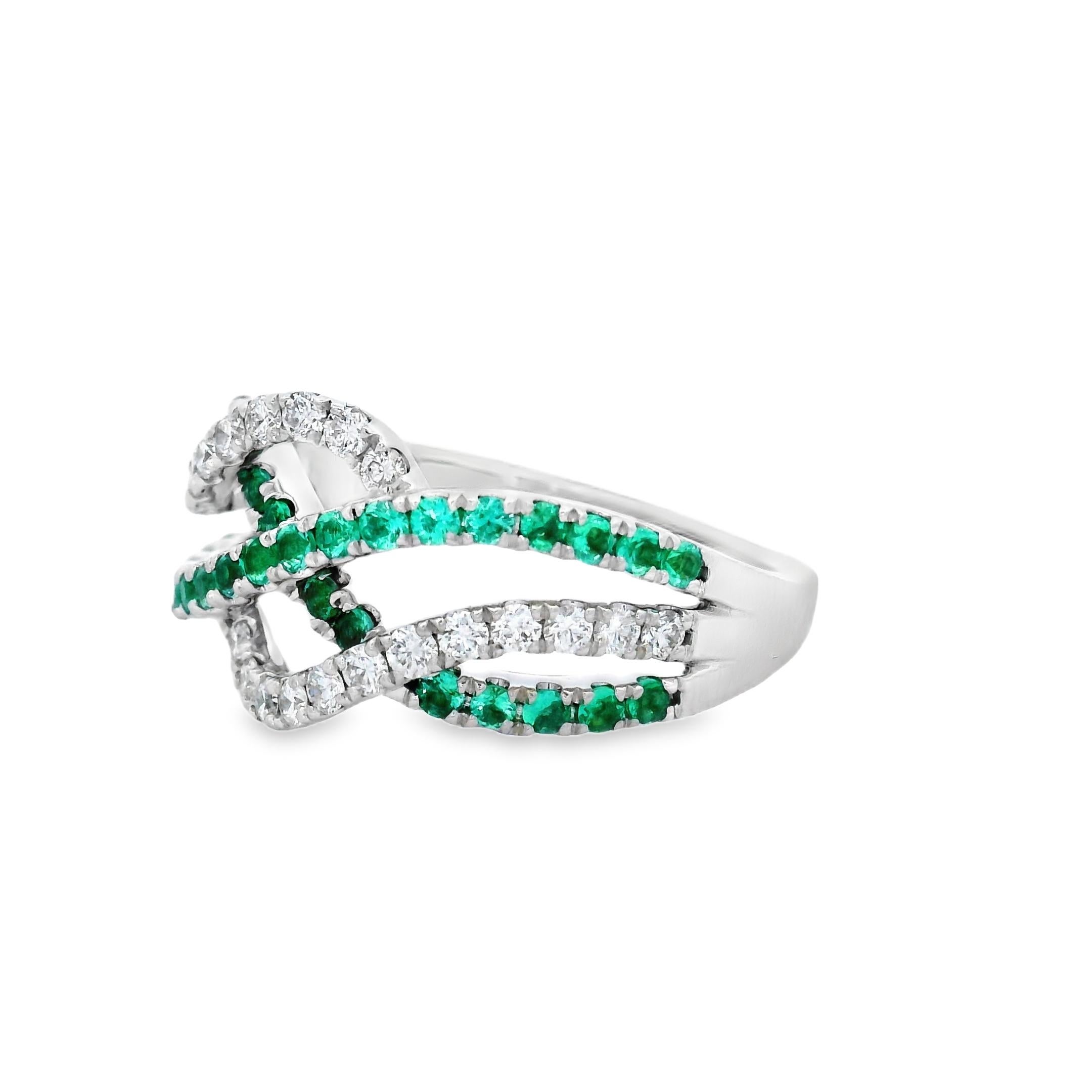 Elegant in motion and rich in contrast, this crossover band ring features a graceful intertwining of round emeralds and diamonds, set in polished 14K white gold. The design weaves alternating rows of vibrant green and sparkling white across the