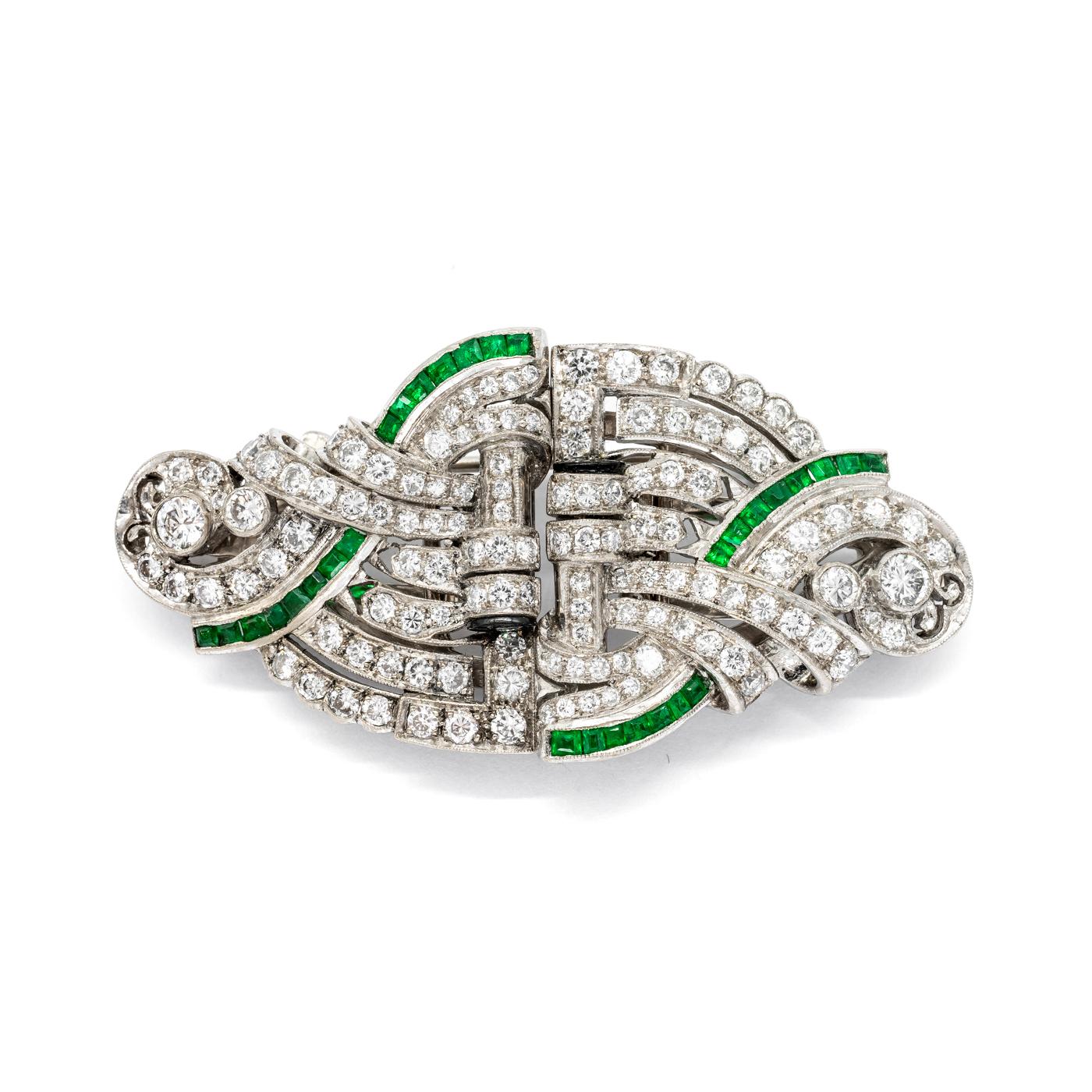 An Art Deco emerald and diamond double clip brooch, set with round brilliant-cut diamonds, weighing an estimated 2.60ct, and calibre cut emeralds, with black onyx finials, mounted in platinum with an 18ct white gold removable brooch fitting.