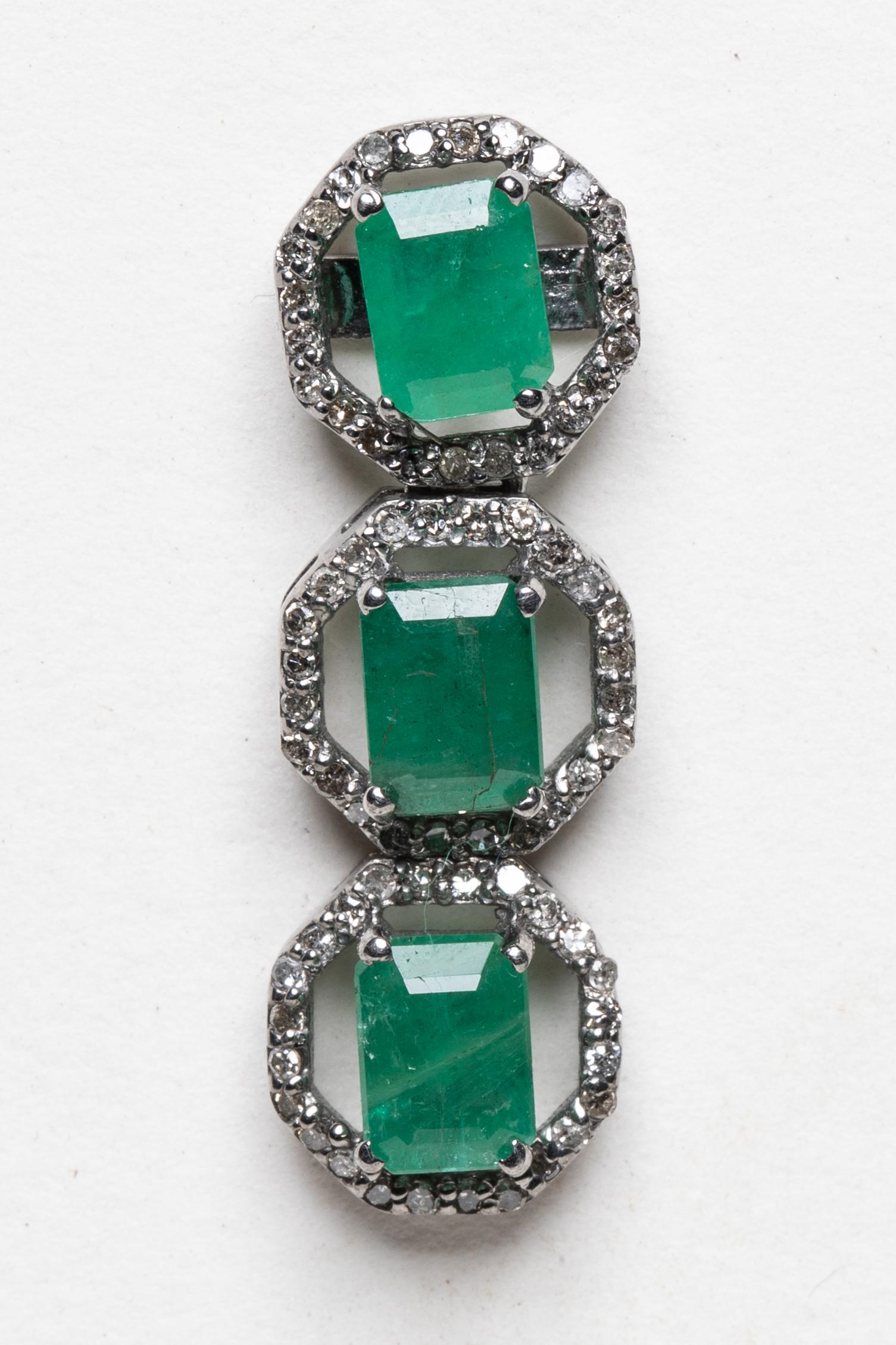 Ein Paar Ohrringe aus kolumbianischem Smaragd mit drei Tropfen im Smaragdschliff. Smaragde sind umgeben von runden Diamanten im Brillantschliff in einer Pave-Fassung in oxidiertem Sterlingsilber in einer dezenten achteckigen Form. 