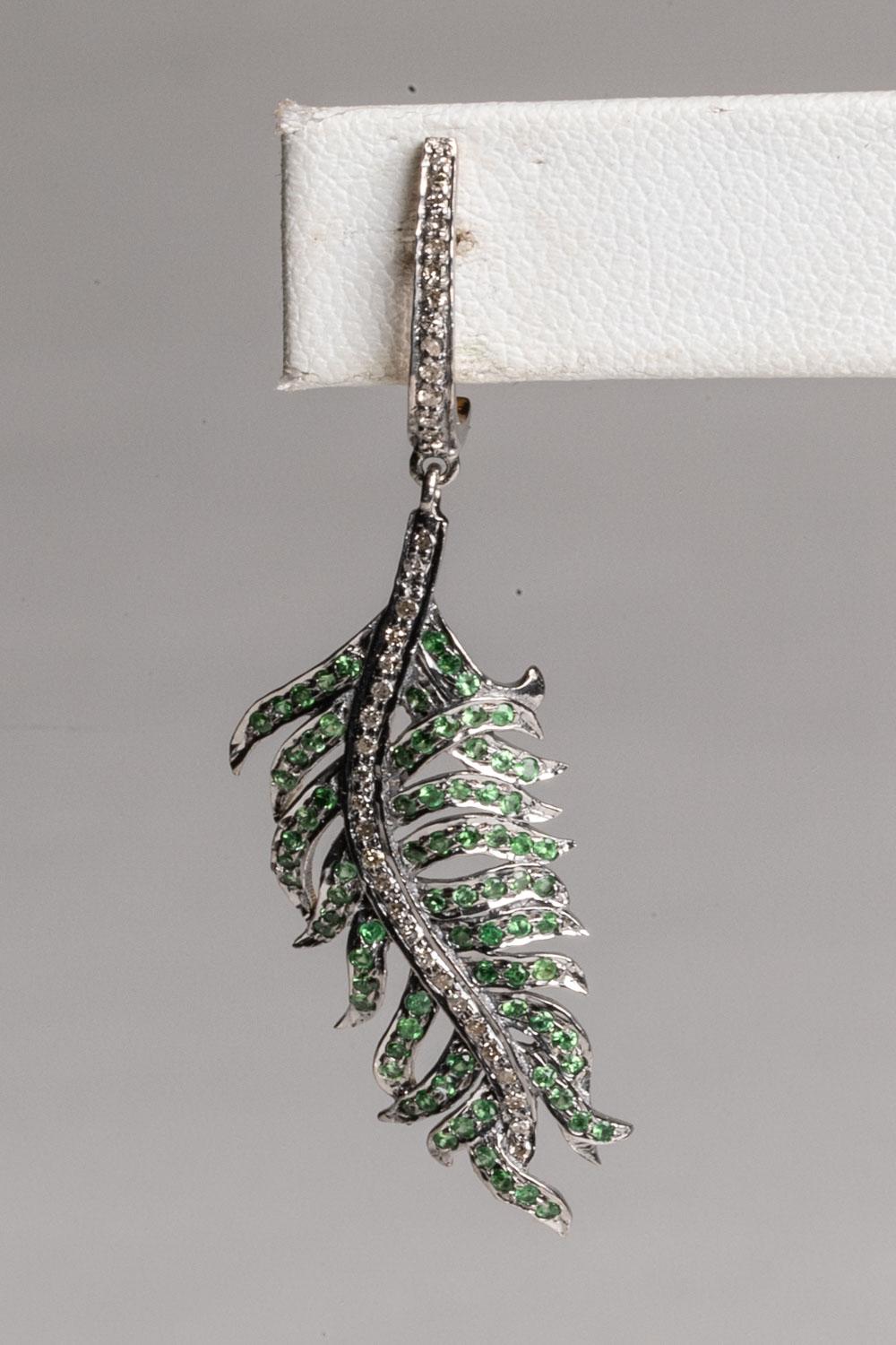 A pair of dangle drop earrings in a leaf design with round, brilliant cut diamonds down the spine, and features round, faceted emeralds as the leaves.  All in a pave`, sterling silver setting. 18K gold post for pierced ears. Total weight of stones