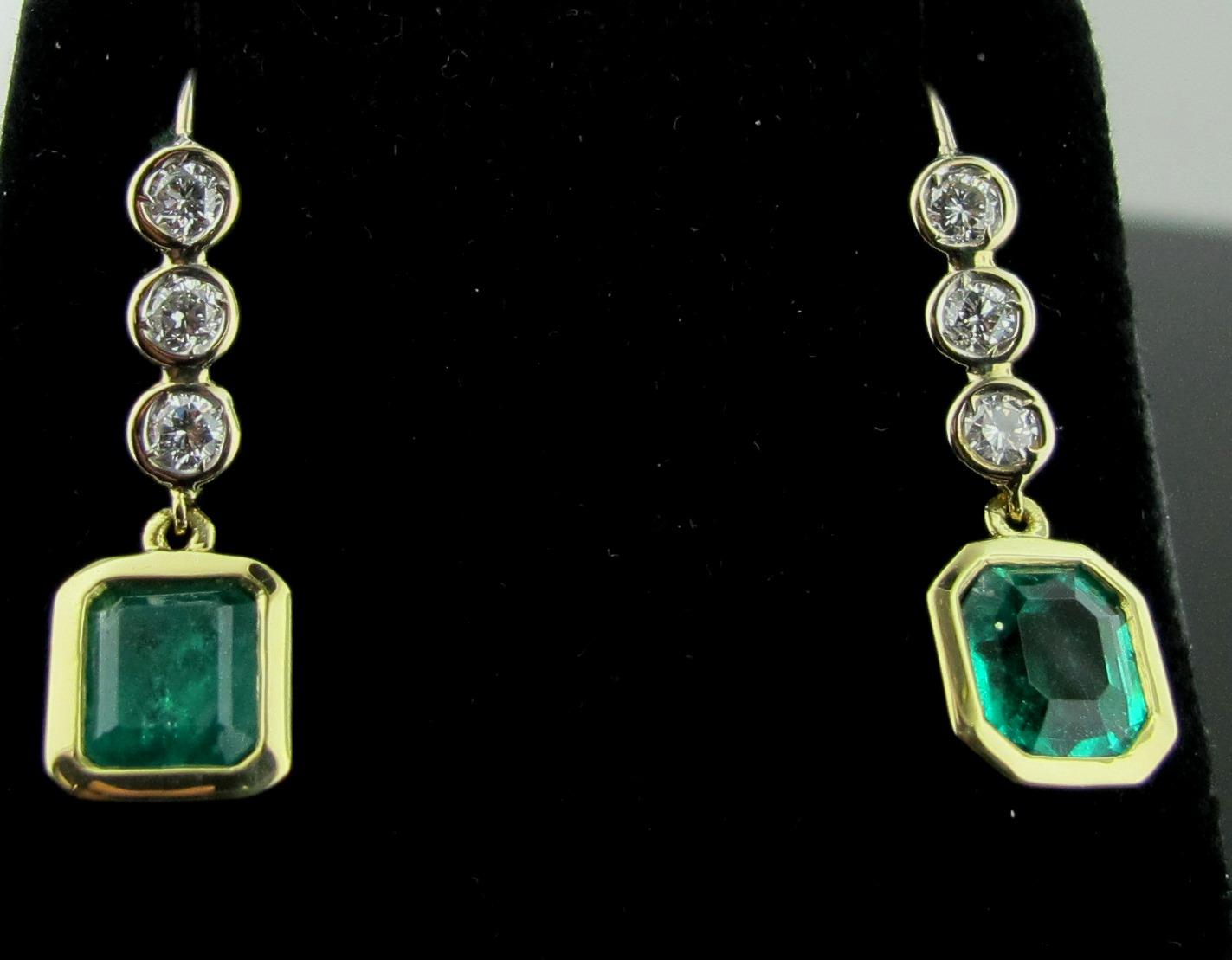 These earrings have 3 round brilliant cut diamonds on the 14 karat white gold posts.  Total diamond weight is 0.42. Color is G-H, Clarity is SI-1.  At the bottom are 2 Emeralds - one is an Emerald cut and one is an Oval cut - both are surrounded in