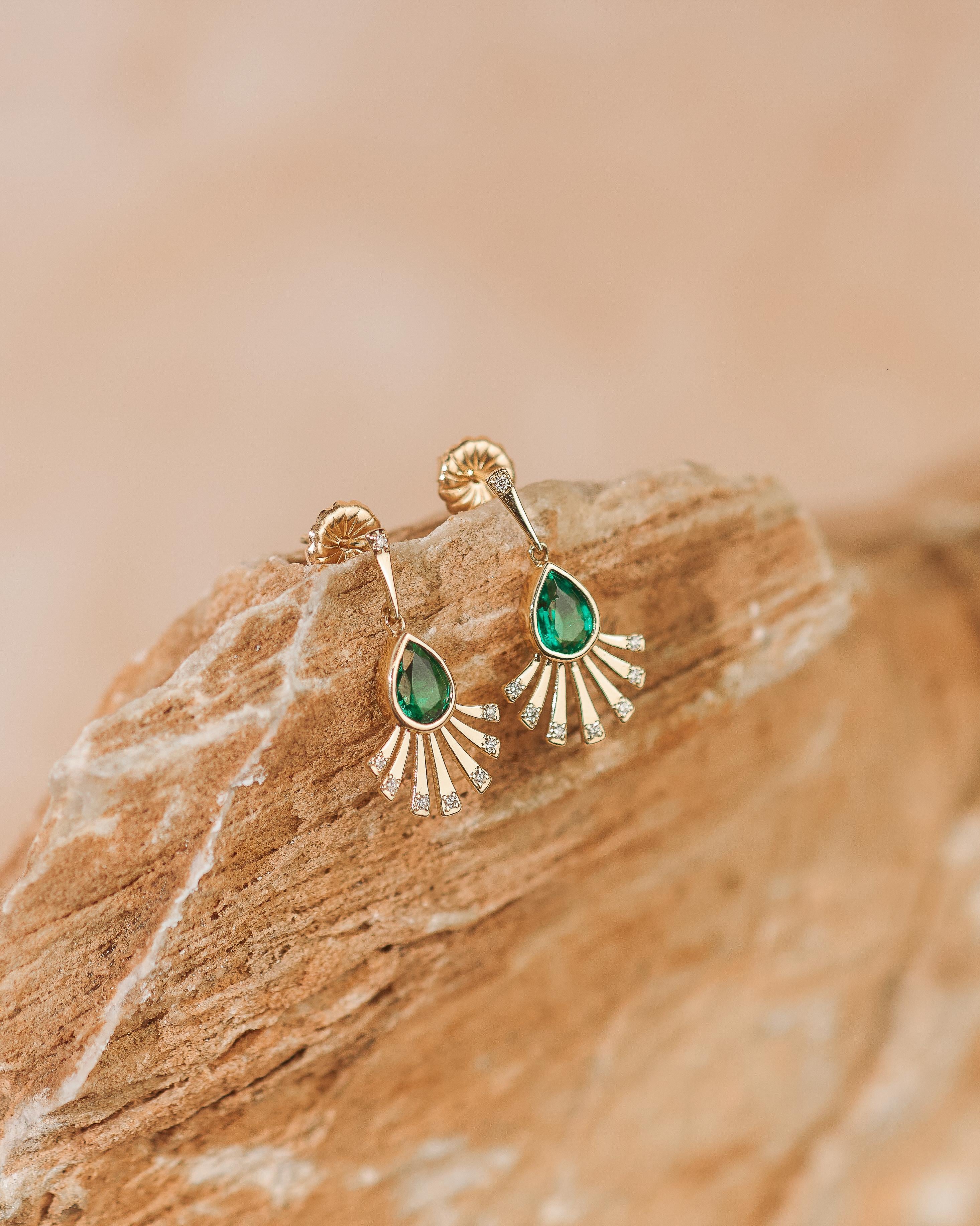 Ces boucles d'oreilles uniques sont composées de deux émeraudes naturelles en forme de poire d'excellente qualité, entourées d'un éventail d'or et de diamants naturels. Chaque émeraude en forme de poire mesure 7 x 5 mm et les deux ensemble