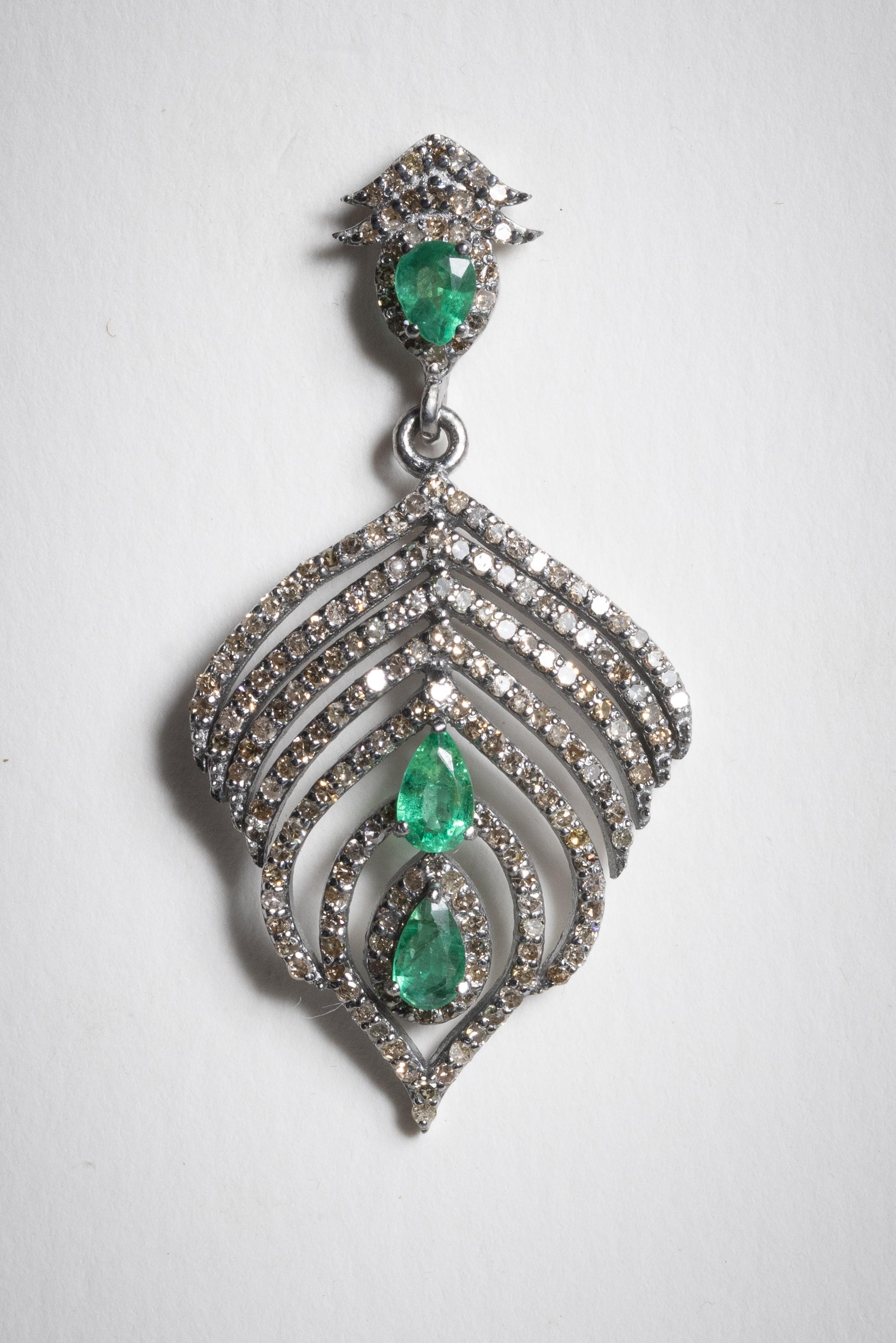 In a stylized peacock feather design, these earrings feature faceted, pear shaped emeralds with faceted, round pave`-set diamonds.  Set in sterling silver with an 18K gold post for pierced ears.  Emeralds total 1.18 carats, Diamonds total 2.48 