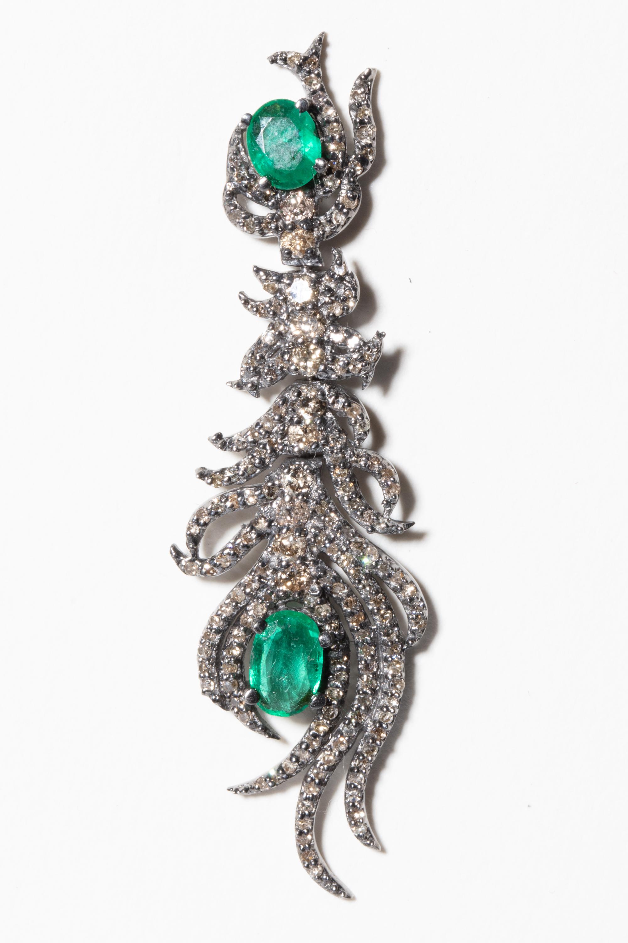 A pair of faceted emerald and pave-set diamond earrings in a stylized peacock feather design.  Larger bezel set diamonds down the spine which is hinged in two places to provide movement and articulation.  Set in sterling silver with an 18K gold post