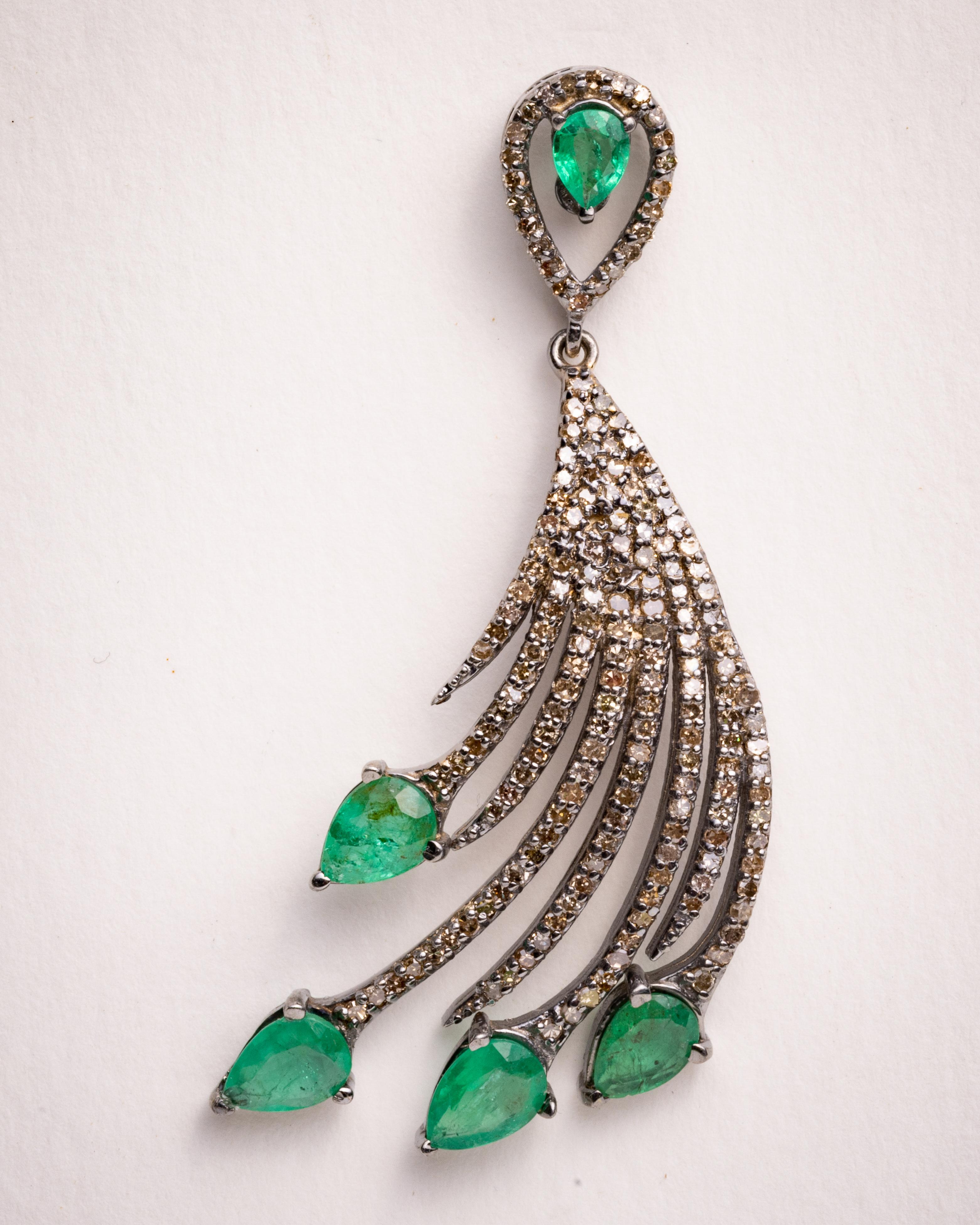 A pair of sweeping feather-motif earrings.  Five pear-shaped, faceted emeralds per earring with round, brilliant cut diamonds in a pave` setting.  Diamonds total 2.65 carats; emeralds total 4.78 carats.  Set in sterling silver and an 18K gold post