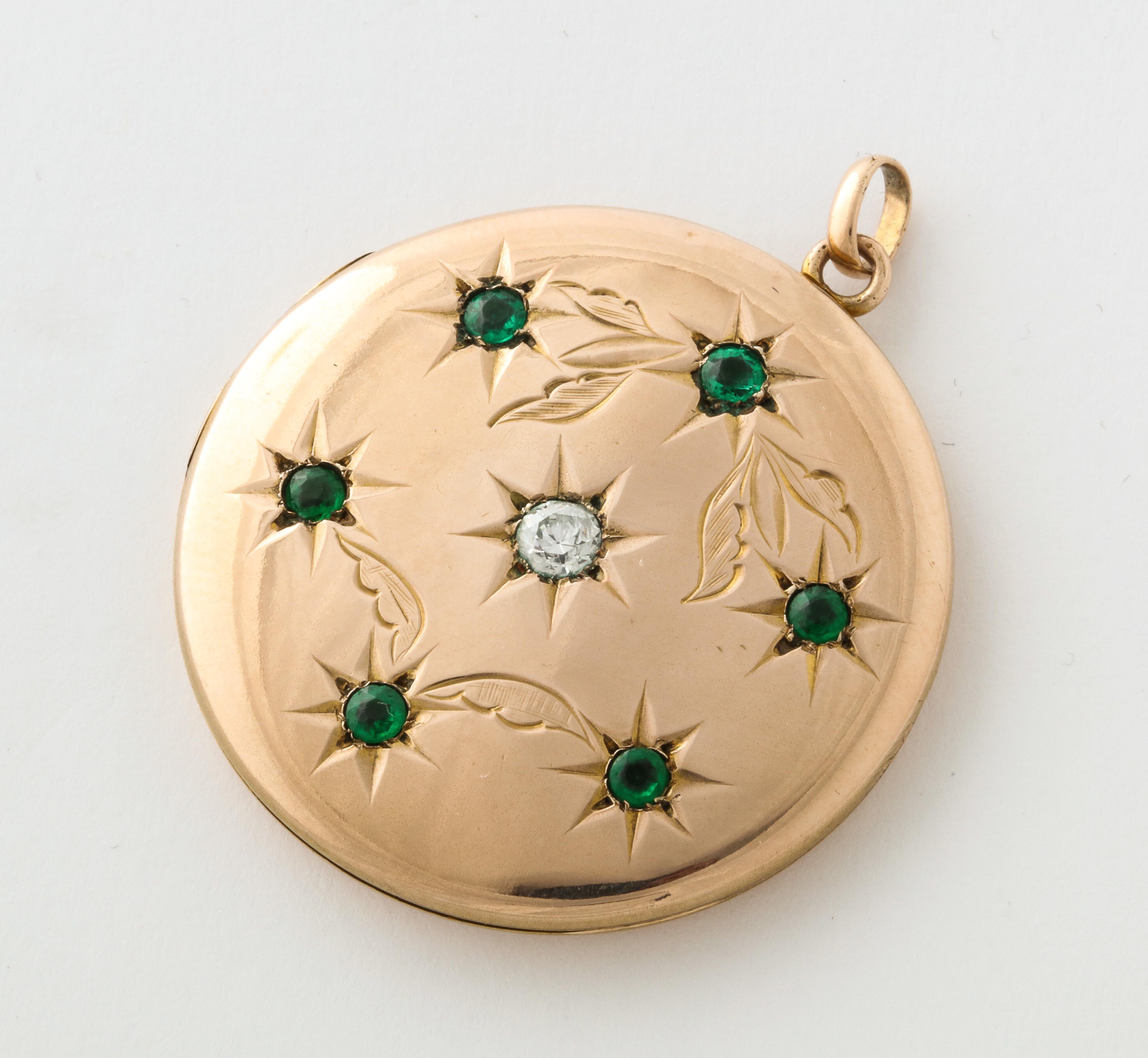 A wonderful Emerald and Diamond Floral Engraved Locket with center diamond, surrounded with emeralds set in a chased floral design. 