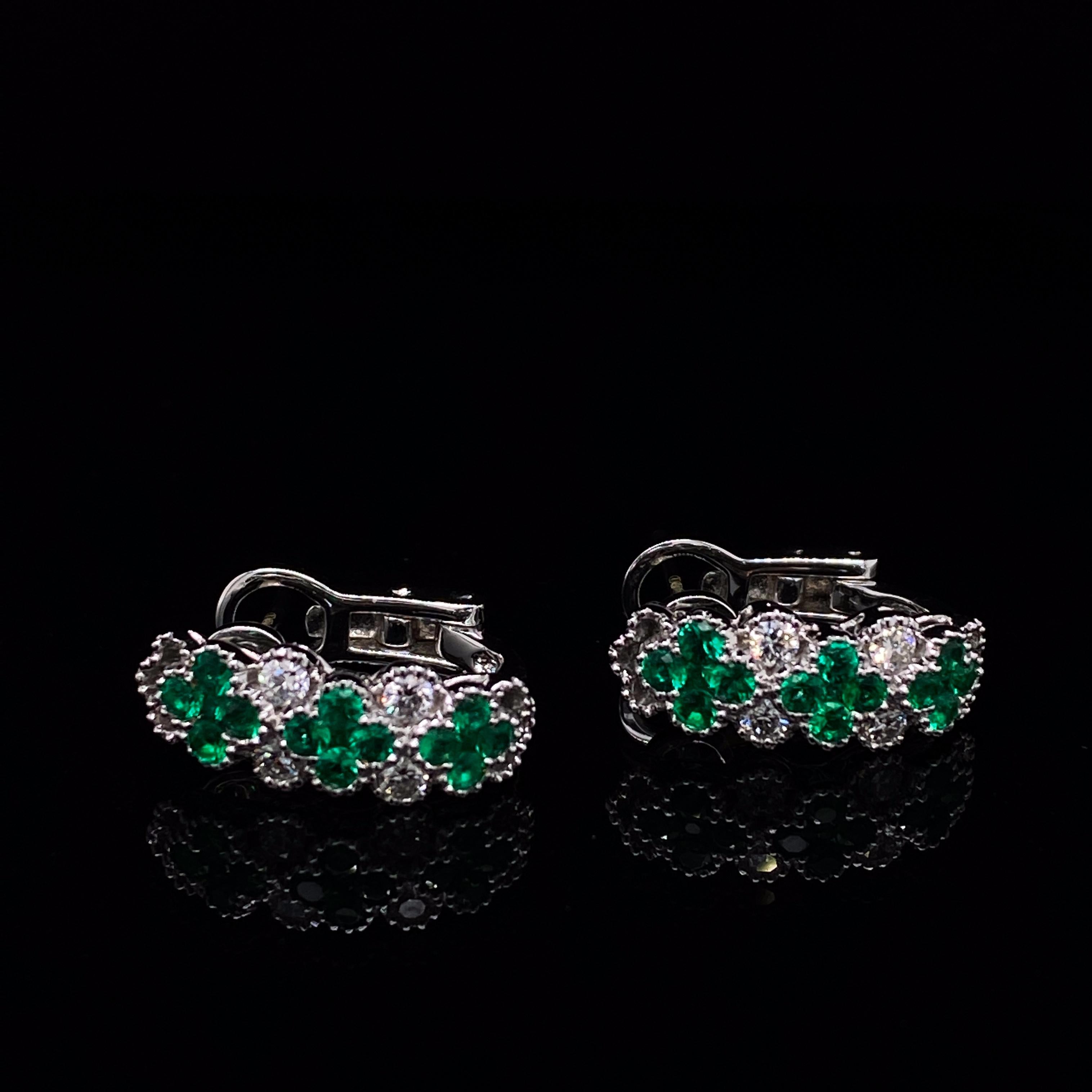 A pair of emerald and diamond floral hoop earrings 18 karat white gold.

These vibrant emerald and diamond hoop earrings are set on a claw setting which show off the emerald colour to great effect.
Comprised of three flowers formed by 4 individual