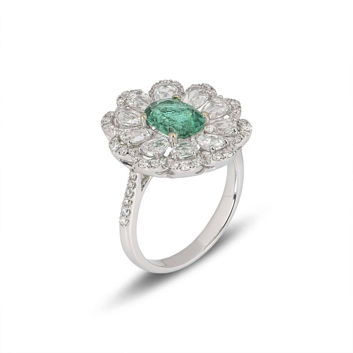 A beautiful 18k white gold flower ring. The ring is set to the centre with an oval cut emerald weighing 1.35ct, displaying a bright even tone. Surrounding the emerald are pear shape double rose cut diamonds and round brilliant cut diamonds totalling