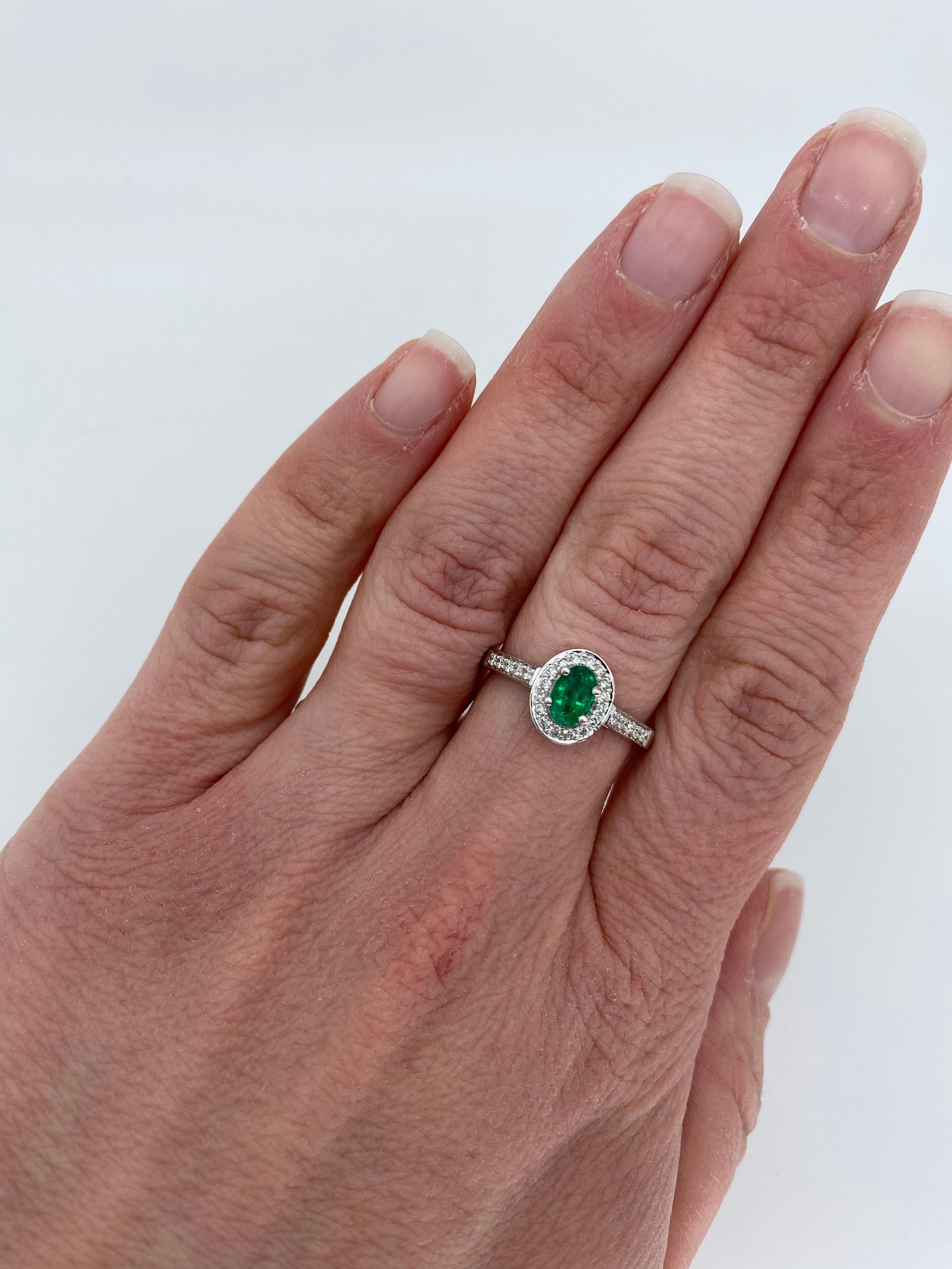 Halo style emerald and diamond ring crafted in 14k white gold. 

Gemstone: Emerald & Diamonds
Gemstone Carat Weight: Oval Cut Approximately .48CT Emerald
Diamond Carat Weight: Approximately .25CTW 
Diamond Cut: Round Brilliant Cut Diamonds
Color: