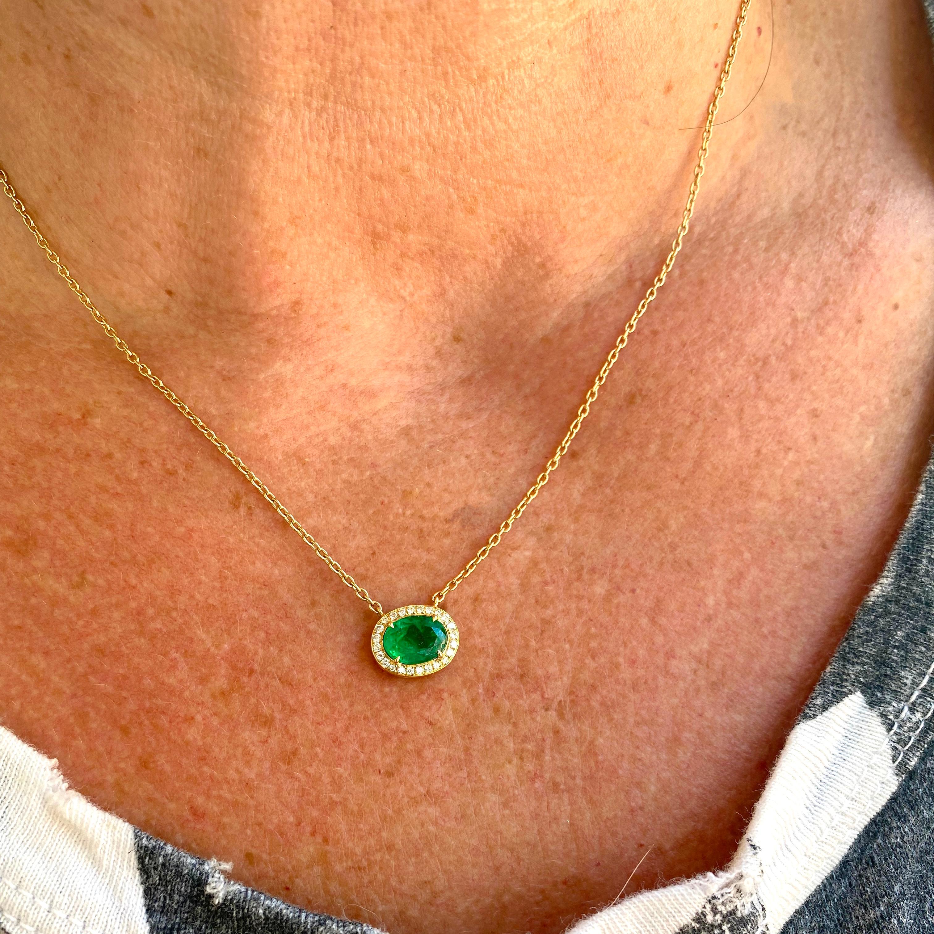 Green glory! This 18k yellow gold necklace is designed with an east-west set vibrant oval emerald weighing 1.43 carats, with a frame of round brilliant-cut diamonds weighing in total 0.14-ct. The necklace weighs 5.1 grams, and can be worn at 16, 17,