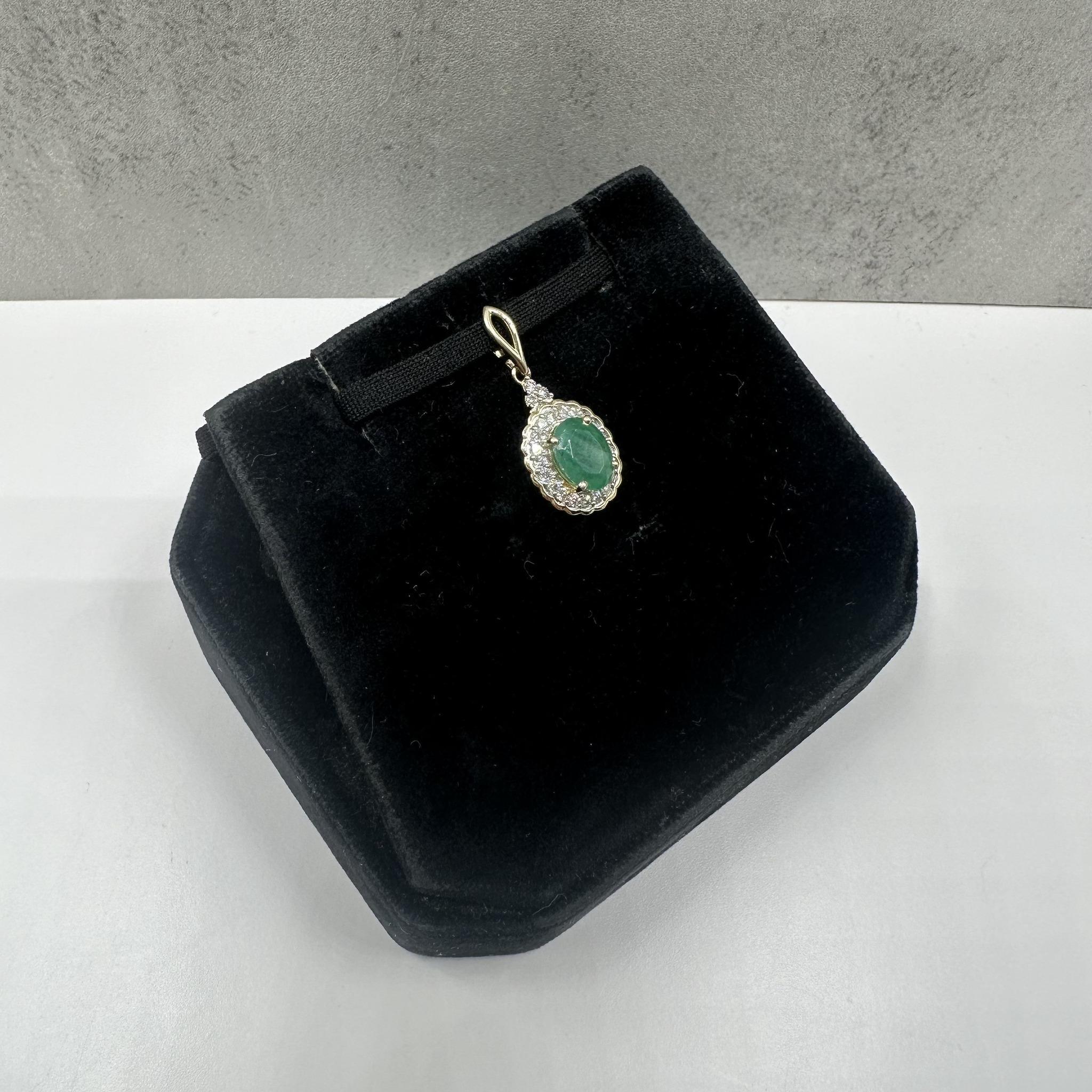 Questa elegante collana di smeraldi e diamanti in oro giallo 10 carati presenta uno smeraldo naturale dal taglio ovale di circa 7x5,2 mm, arricchito da diamanti tondi naturali GH SI2-I1 per un peso totale di 0,18 carati. Lo smeraldo verde intenso