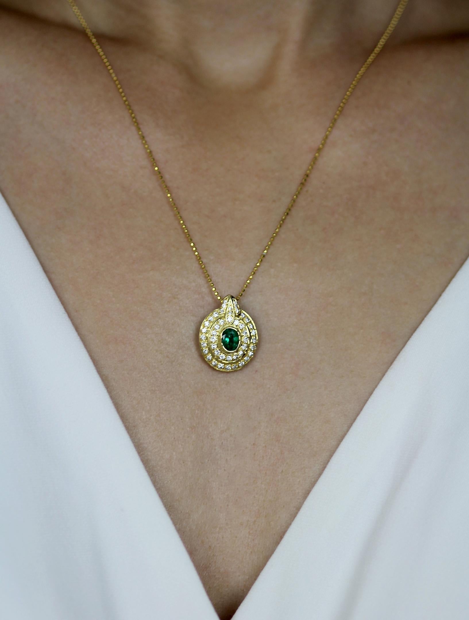 A stunningly unconventional yellow gold and emerald pendant reminiscent of an exotic tortoise motif. The  central wildlife-green oval emerald is encircled by two accented diamond encrusted borders, which both contrast with and compliment the deep