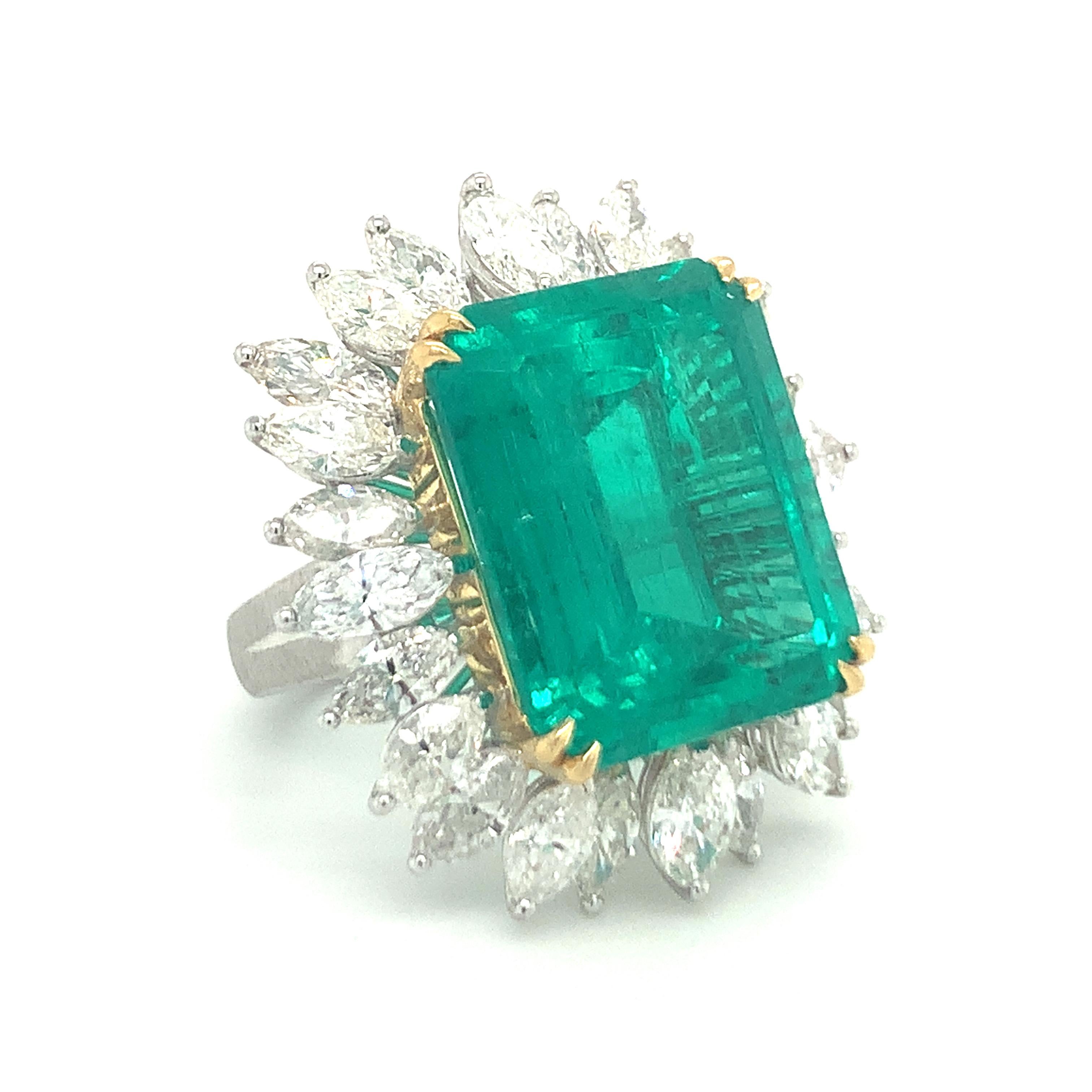 This phenomenal ring centers a breathtaking 19.34-carat emerald cut emerald, certified by GIA Report No. 2225667781 as of Colombian origin, prong-set in a luxurious blend of platinum and 18K yellow gold. The vivid green of the emerald is beautifully
