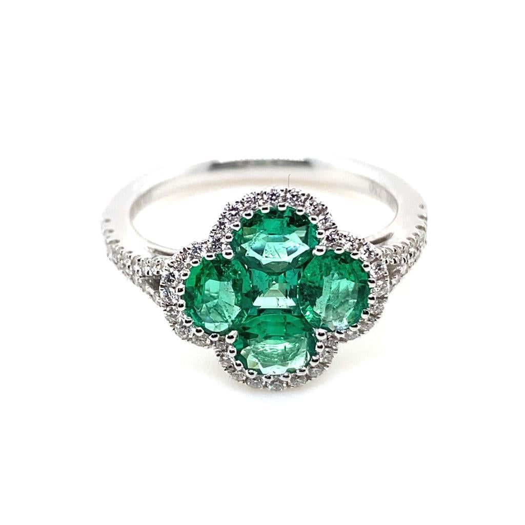 An emerald and diamond quatre foil cluster 18 karat white gold engagement ring.

This ring is designed as four oval cuts and a centre square cut emerald to form a distinctive stylized quatre foil shape, set within a fine diamond set border leading