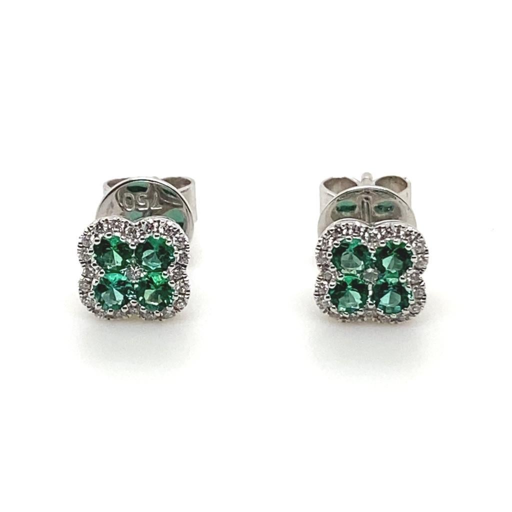 A pair of emerald and diamond quatrefoil cluster earrings in 18 karat white gold.

Each of these elegant stud earrings comprise of four beautiful round brilliant cut emeralds of fine quality in a quatrefoil design set within a border of sparkling