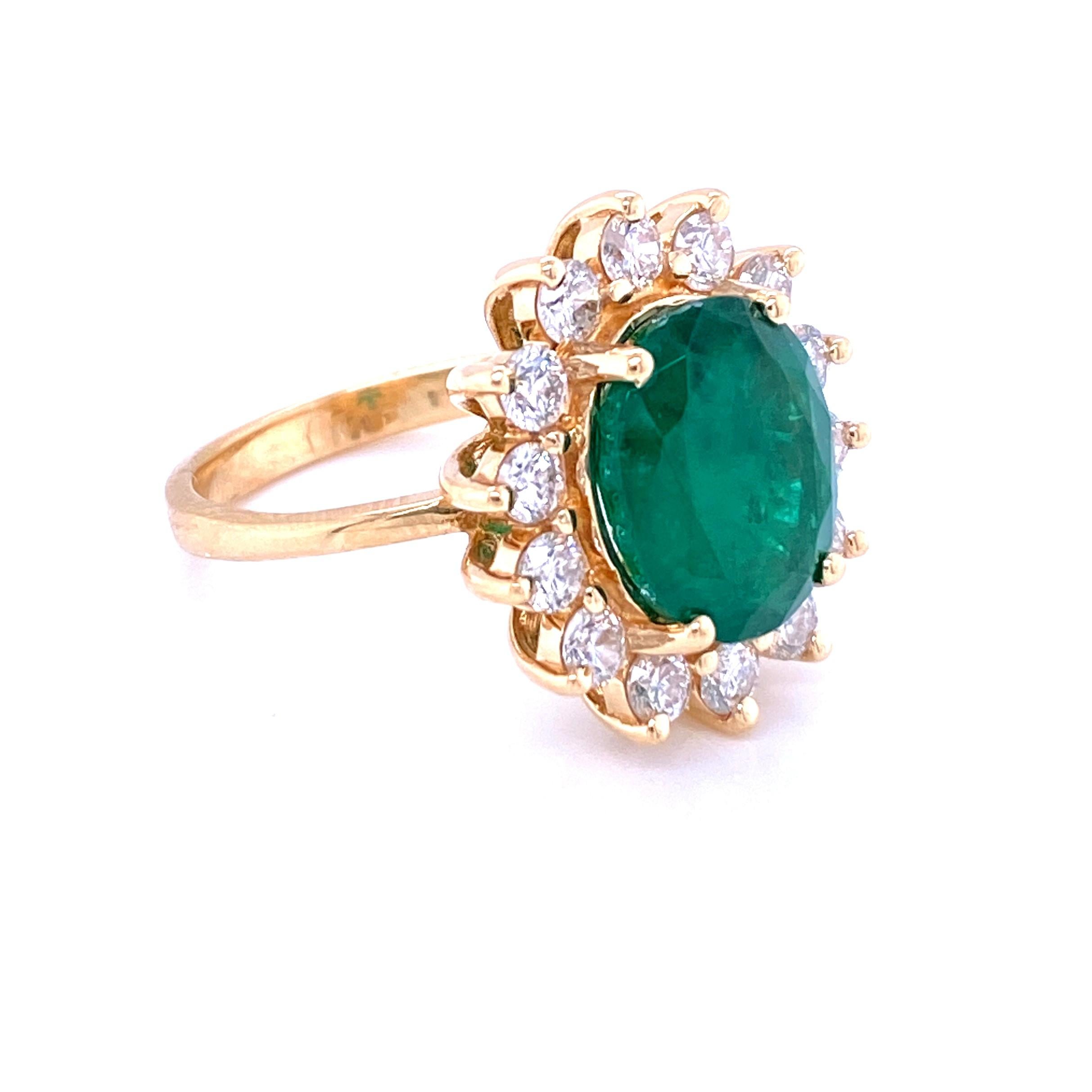 14 karat yellow gold (stamped 14K EFFY) ring set with one 10.8x9mm oval emerald surrounded by fourteen round brilliant diamonds, approximately 1.00 carat total weight with matching H/I color and I1 clarity. The shank measures 2.4mm at the base and
