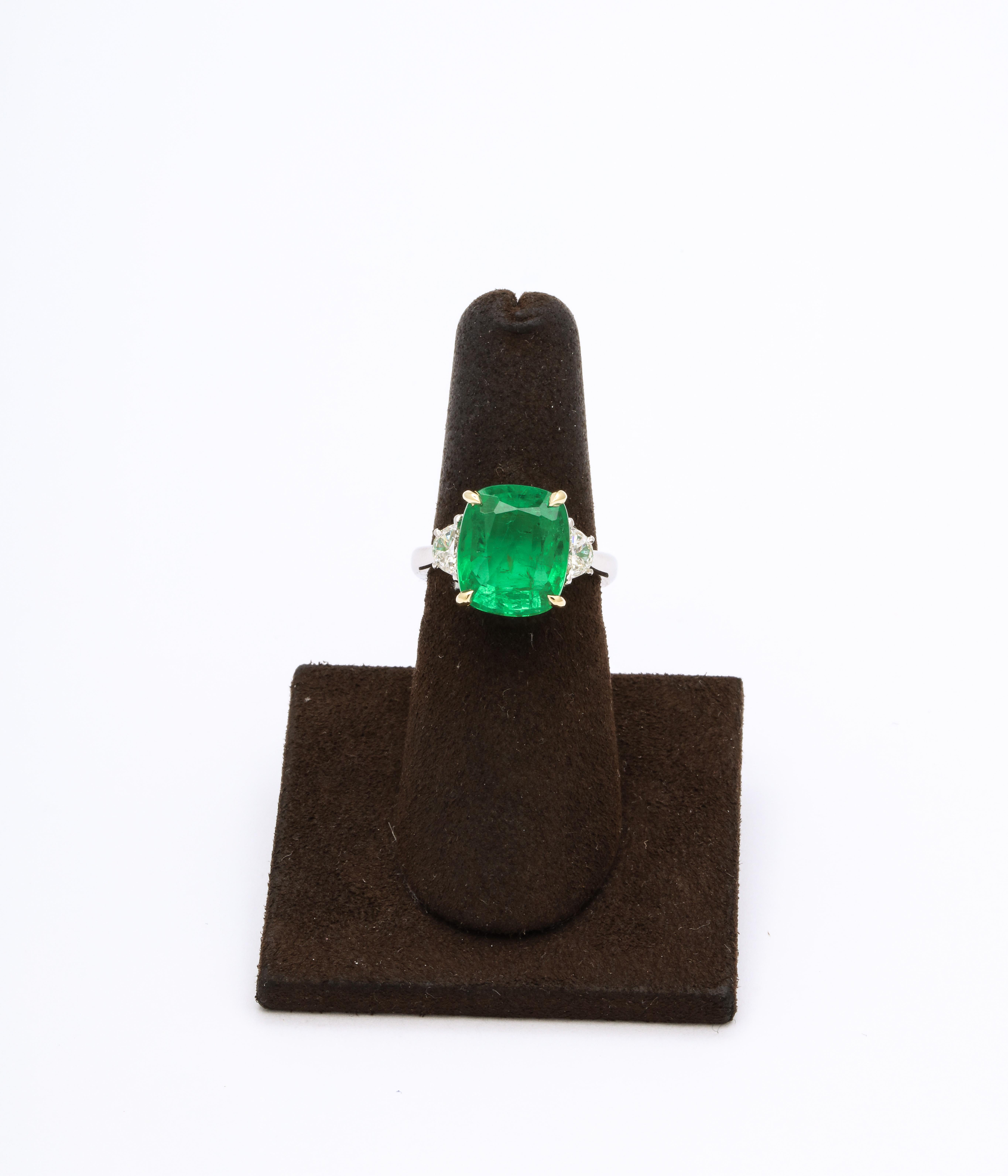 
6.09 carat Certified “Vivid Green” Cushion cut Emerald.

.47 carats of white half moon cut diamonds on the side. 

Custom platinum and 18k yellow gold setting. 

Currently a size 6, this ring can easily be sized. 

A beautiful emerald with fabulous