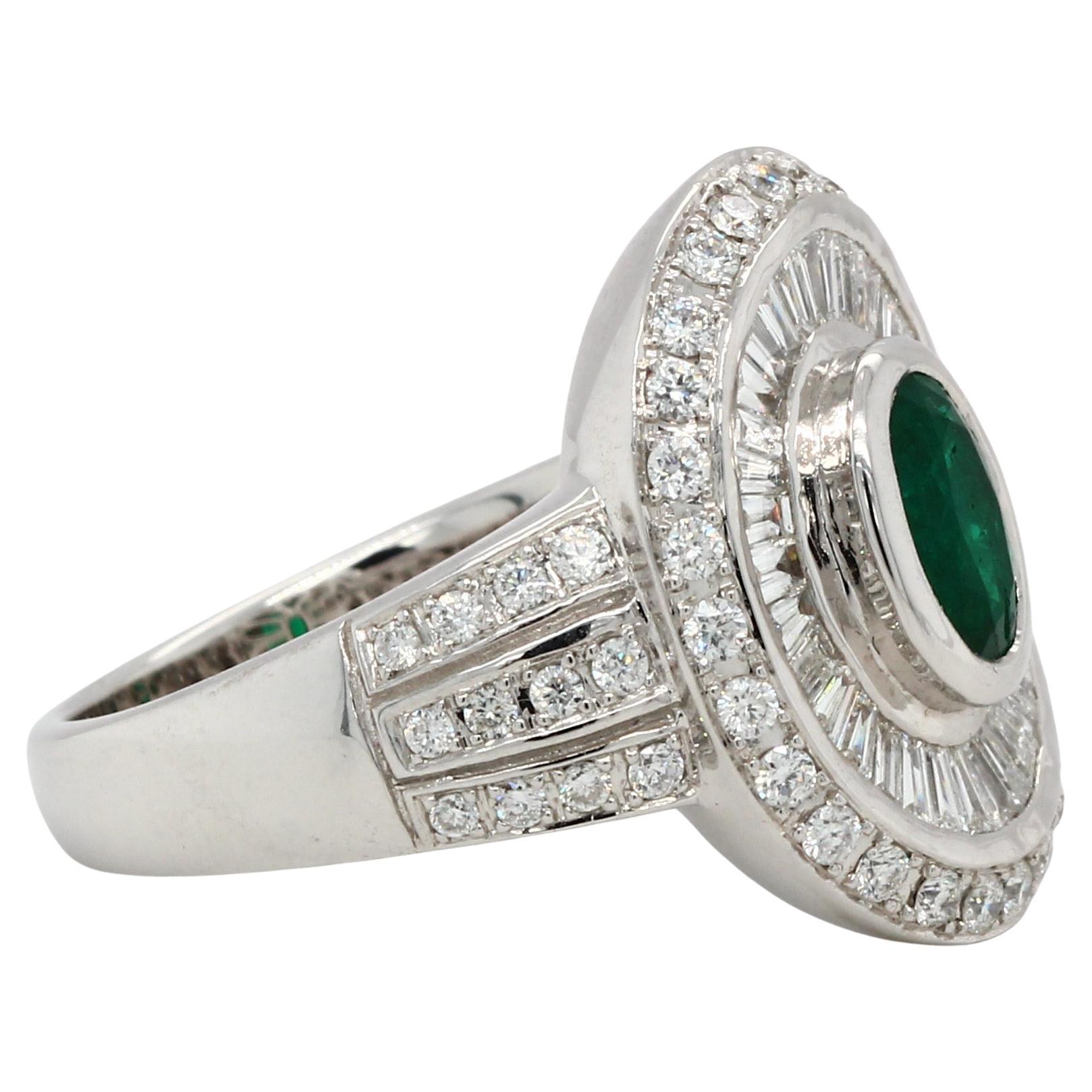 A brand new emerald and diamond 18K gold ring. A 0.92 carat emerald oval shape is set in this ring, which also includes a 0.52 carat diamond tapper and a 0.53 carat diamond round. This ring weighs 9.28 grams and is composed of 18K white
