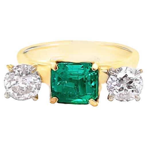 Three stone diamond and Emerald stone center with one round brilliant white diamond on each side. The yellow-gold retro cocktail ring is designed with a modern twist. The center stone is a 1.51-carat emerald-shaped emerald. The two white round