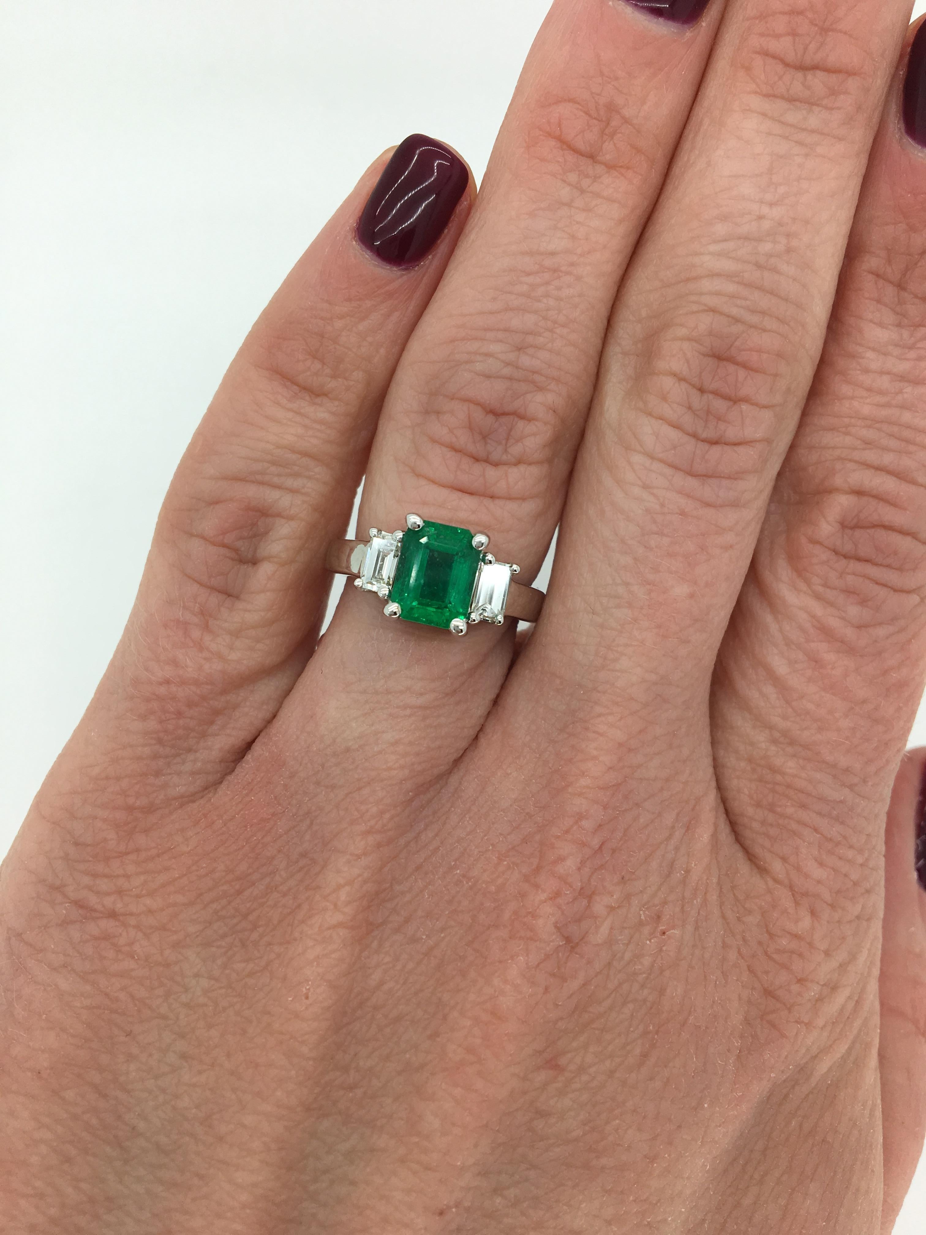 Classic three stone Emerald ring with flanking Emerald Cut Diamonds crafted in 14K white gold. 

Gemstone: Emerald & Diamond
Gemstone Carat Weight: Approximately 1.65CT Emerald
Diamond Carat Weight:  Approximately .39CTW
Diamond Cut: Emerald