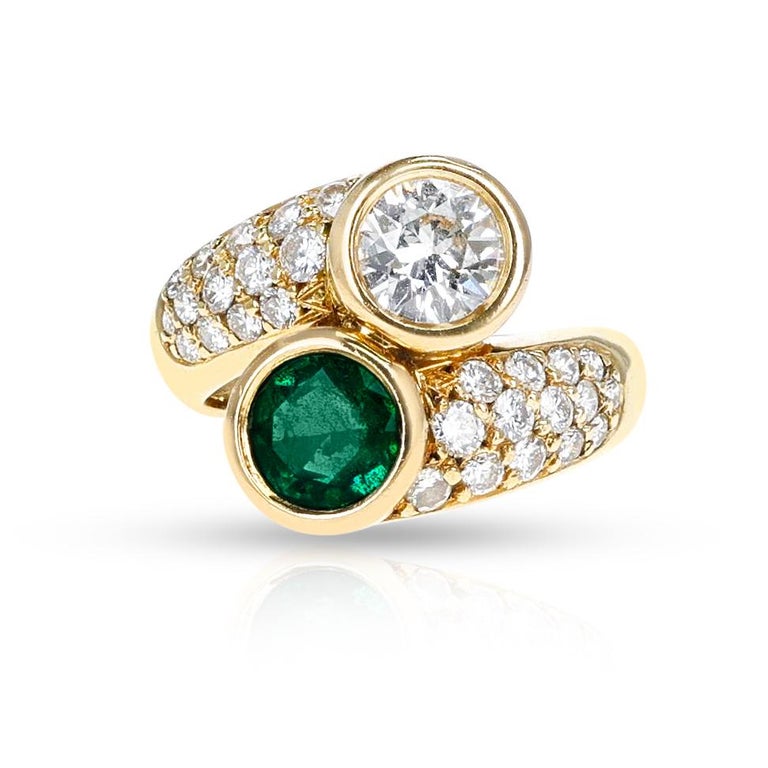 An Emerald and Diamond Toi et Moi Ring, 18k. The diamond weighs appx. 0.70 carats and the emerald weighs appx. 0.50 carats. 

