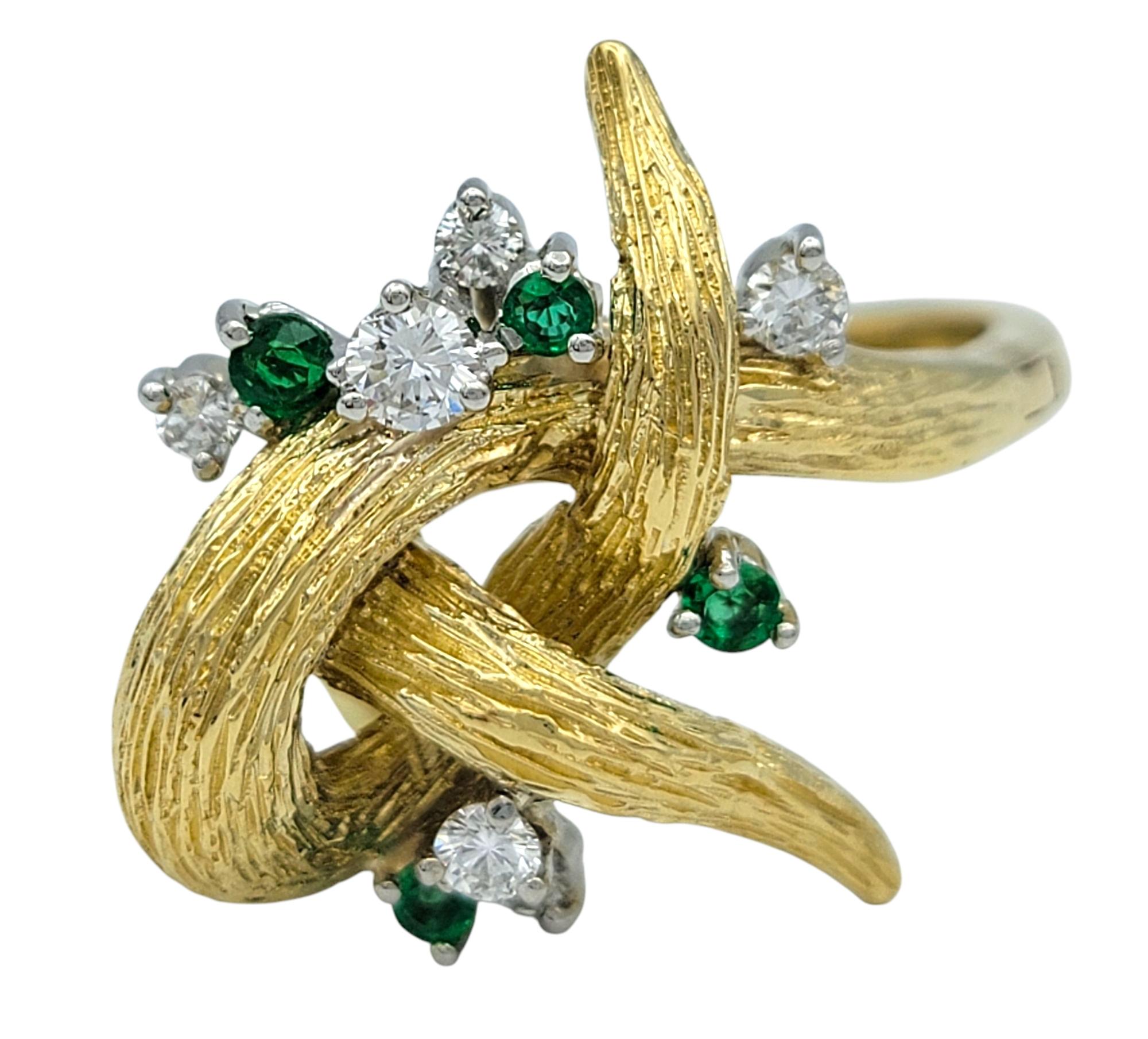 Ring Size: 10.5  (includes arthritic band that can stretch to a size 12.5) 

This bold designer ring features a detailed faux bois style swirl motif in 14 karat yellow gold, accented with alternating green emeralds and white diamonds. The