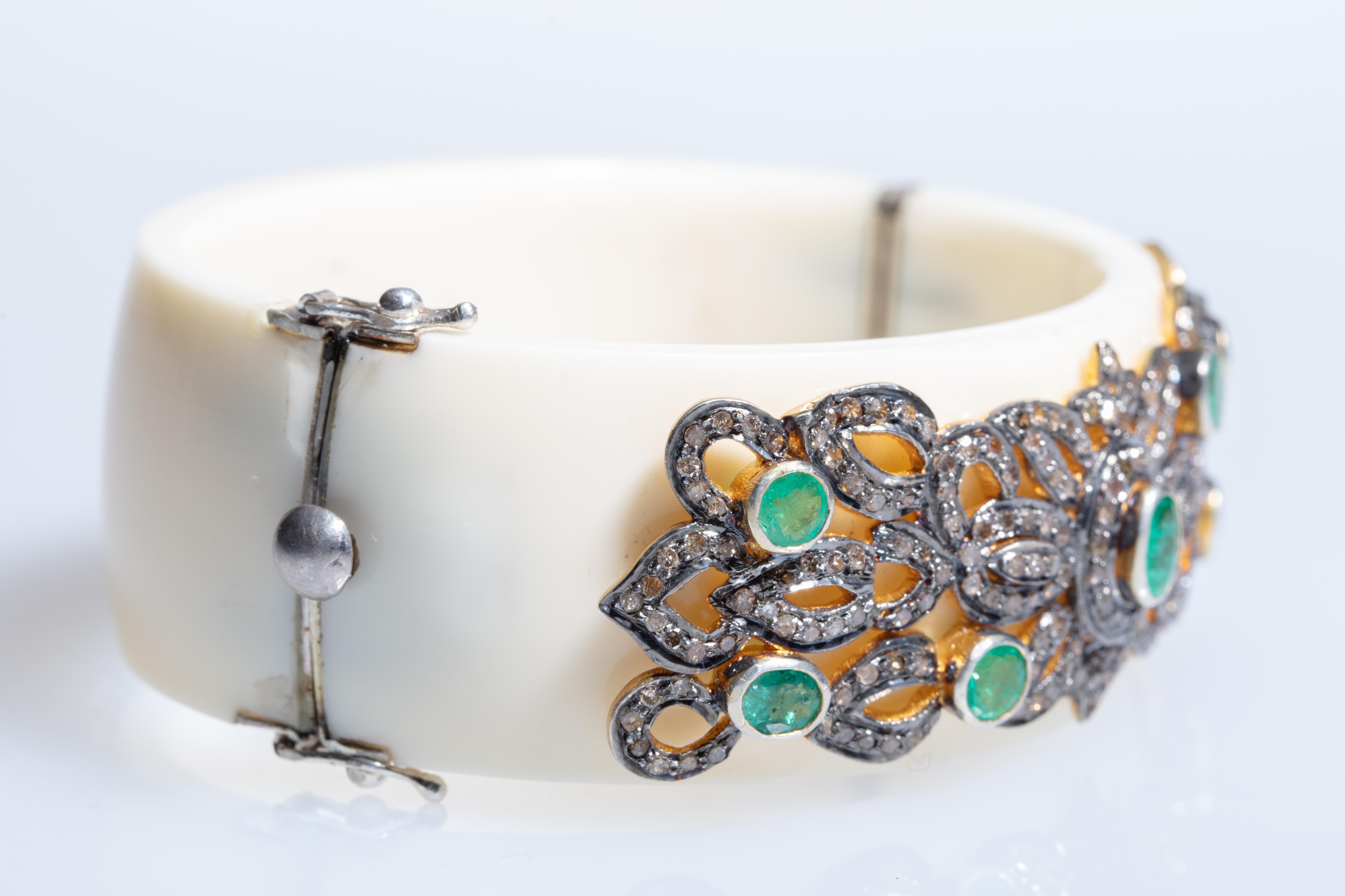 A white Bakelite cuff bracelet with 7 faceted emeralds surrounded by pave' set diamonds in an oxidized sterling silver.  The oval shape of the cuff keeps the workmanship on top of the wrist.  Weight of diamonds is 2.47 carats; emeralds are 2.48