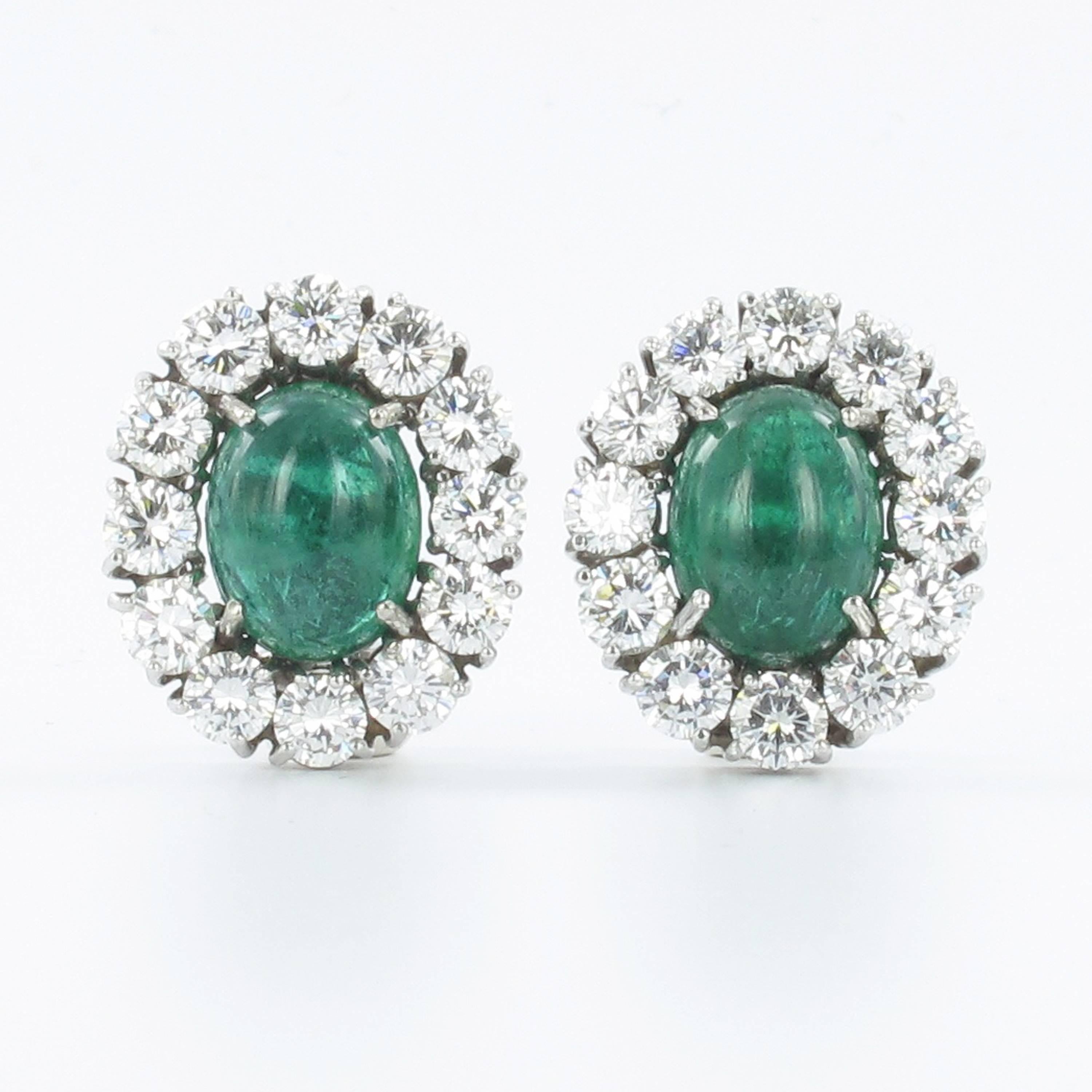 Classic ear clips in white gold 750. Two oval cabochon cut emeralds of approximate 12.5 x 9.5 mm in diameter totaling approximate 10.70 ct. Nice crystal and good color. The emeralds are of Brazilian origin. Entourage set with 24 brilliant cut