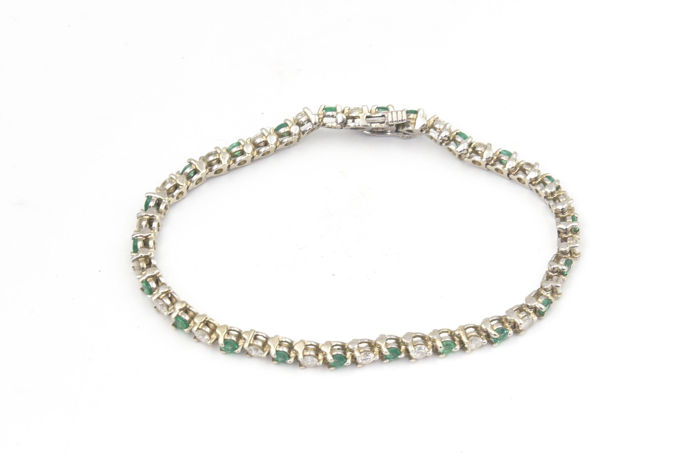 Pulsera de tenis de oro blanco de 14k con 43 esmeraldas redondas y diamantes alternados engastados con tres garras.  La pulsera tiene un cierre de botón y un seguro.  Marcado 14k en el cierre.  Contiene aproximadamente 1,68 quilates en diamantes.