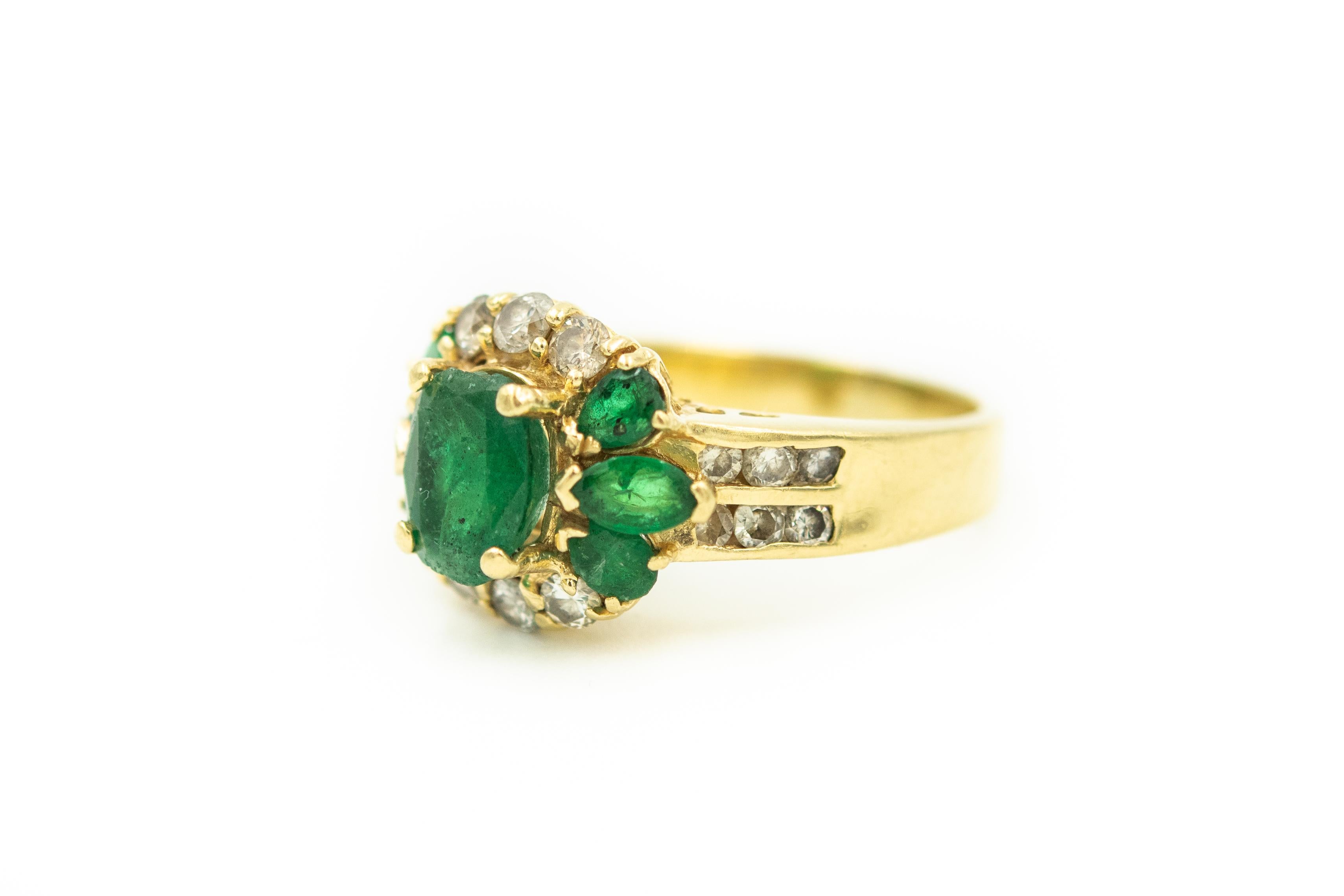Emerald and diamond 18k yellow gold ring with a contemporary band that has 6 round channel set diamonds on either side.  The ring contains a center 4 prong set oval green emerald that weights approximately 1.25 carats. The center is accented by 6 (3