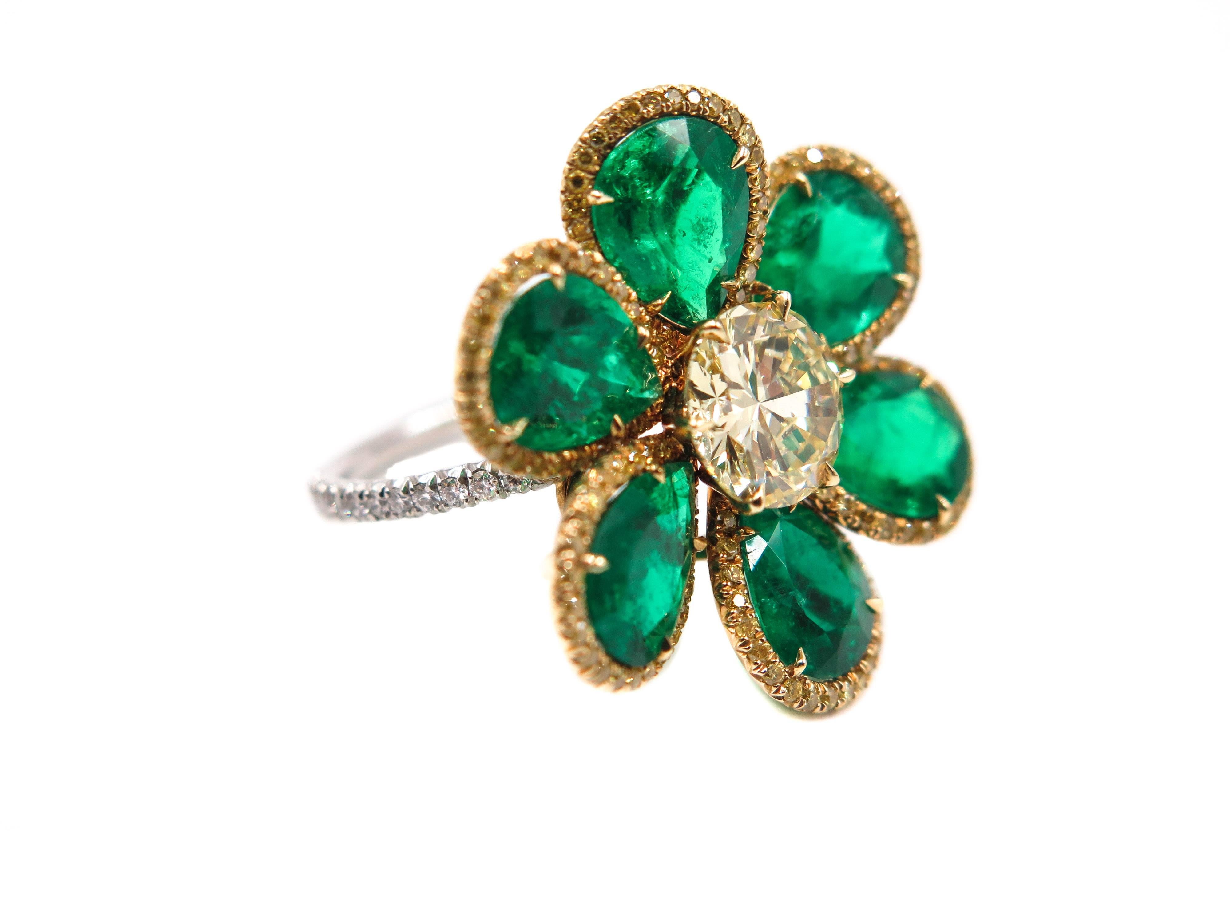 This stunning, fine and impressive emerald and diamond flower ring has been crafted in 18k yellow gold and 18k white gold setting.
The flower style setting is ornamented with a Faint Yellow diamond, VS clarity. This 1.47 carat round brilliant cut