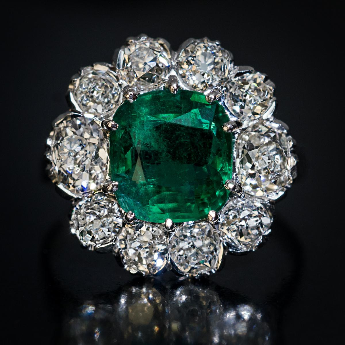 Circa 1950s

A vintage 18K white gold engagement cluster ring is centered with a cushion cut emerald of a deep green color. The emerald is framed by chunky bright white old mine cut diamonds (G-H color, VS2 – SI2 clarity).

The emerald measures 8.28