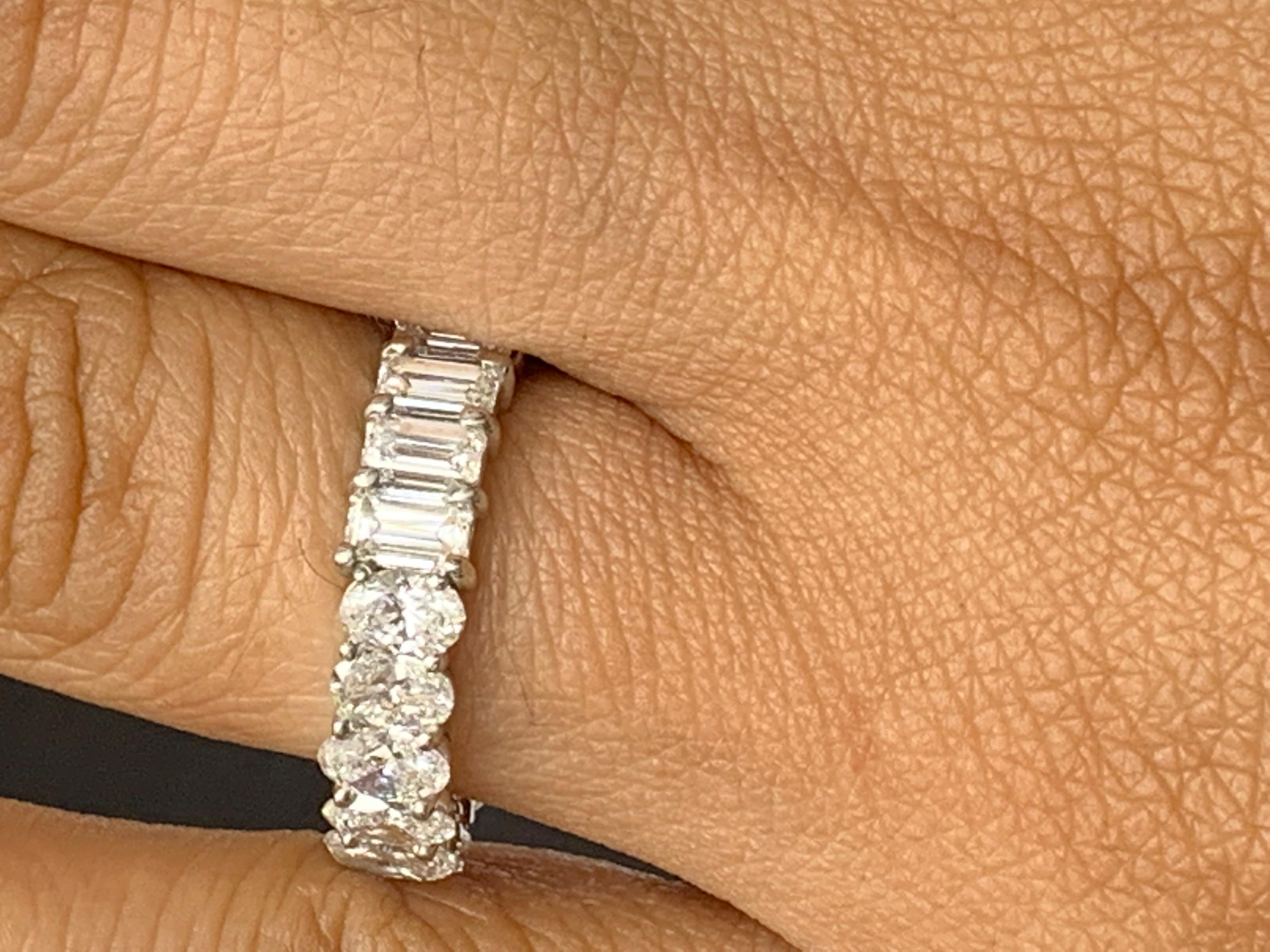 A classic and timeless eternity band style showcasing a row of half emerald cut and half oval cut diamonds set in a shared prong platinum mounting. 11 emerald cut Diamonds weigh 2.56 carats and 10 oval cut diamonds weigh 2.41 carats. Can be