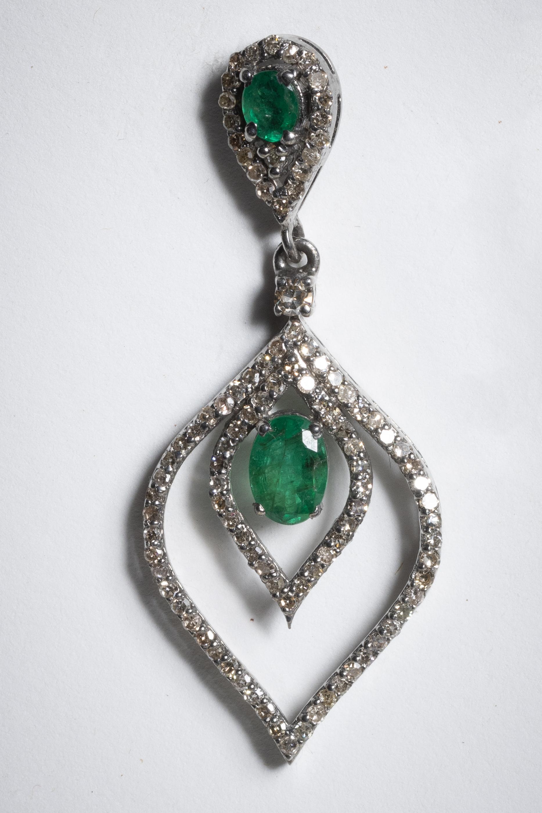 Un paio di orecchini a goccia con smeraldo e diamante.  La montatura e il centro presentano grandi smeraldi ovali sfaccettati e diamanti incastonati lungo il bordo.   Gli smeraldi ammontano a 1,78 carati; i diamanti a 1,48 carati.  Incastonato in