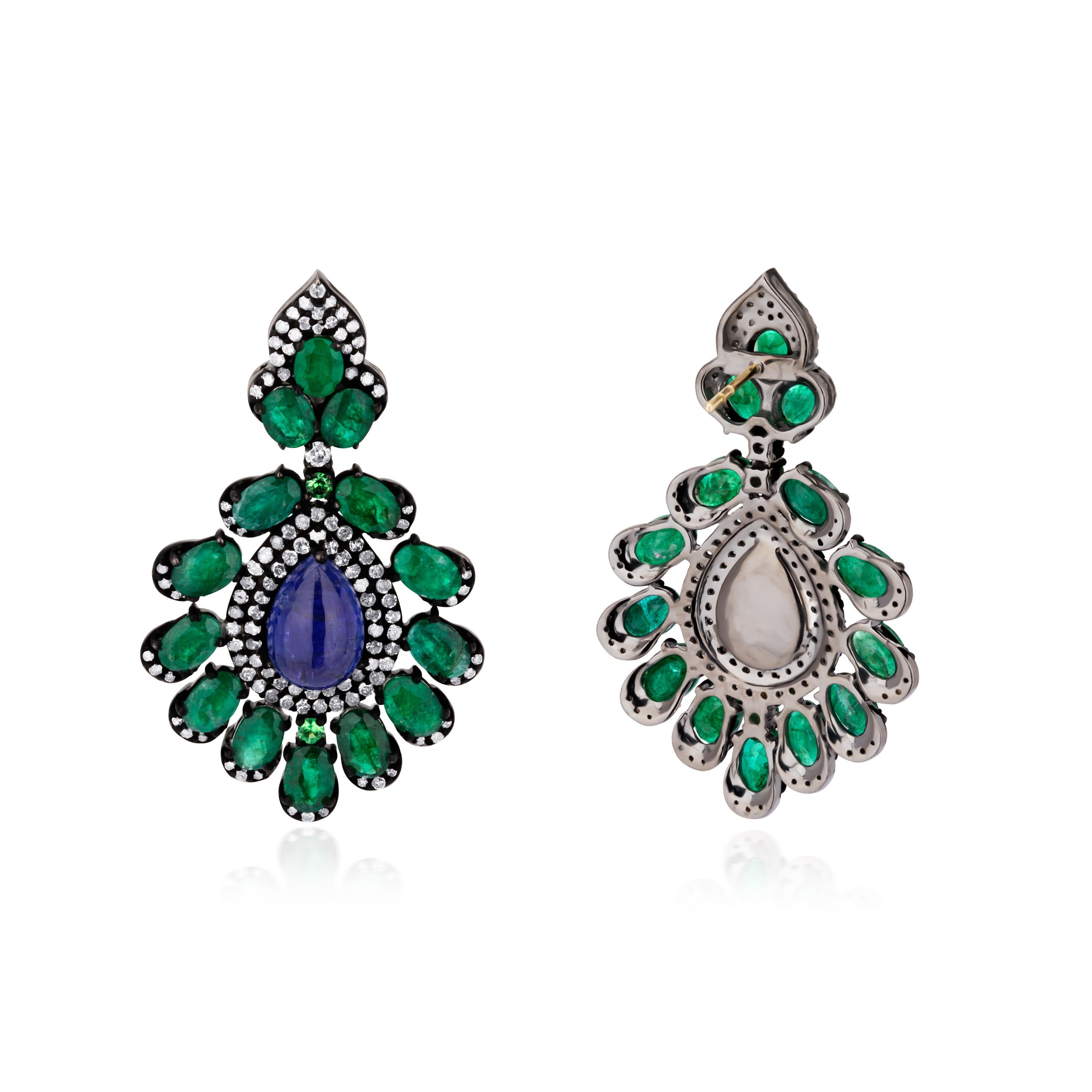 Fun and flirty, these Victorian drop earrings glow at their centers with pear cut tanzanites that are framed inside exquisitely designed frames of faceted emeralds and diamonds. Rendered in 18K gold and 925 sterling silver these stunning earrings