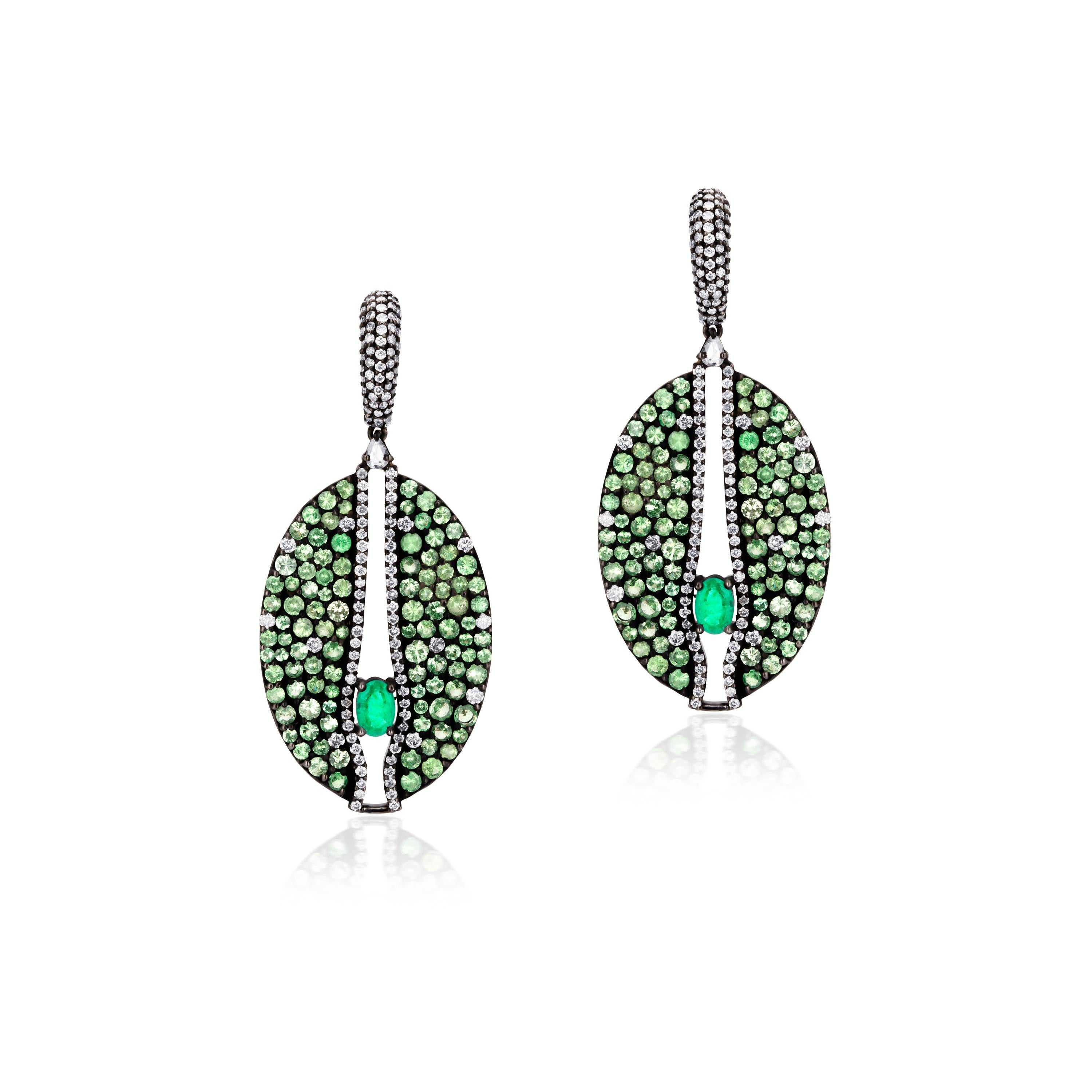 A gorgeously matched pair of unfaltering sparkle. The oval drops in black metal sparkle with dots of brilliant cut prong set green round tsavorietes and diamonds. The open space between the two parts of the oval drop is dotted with lines of round