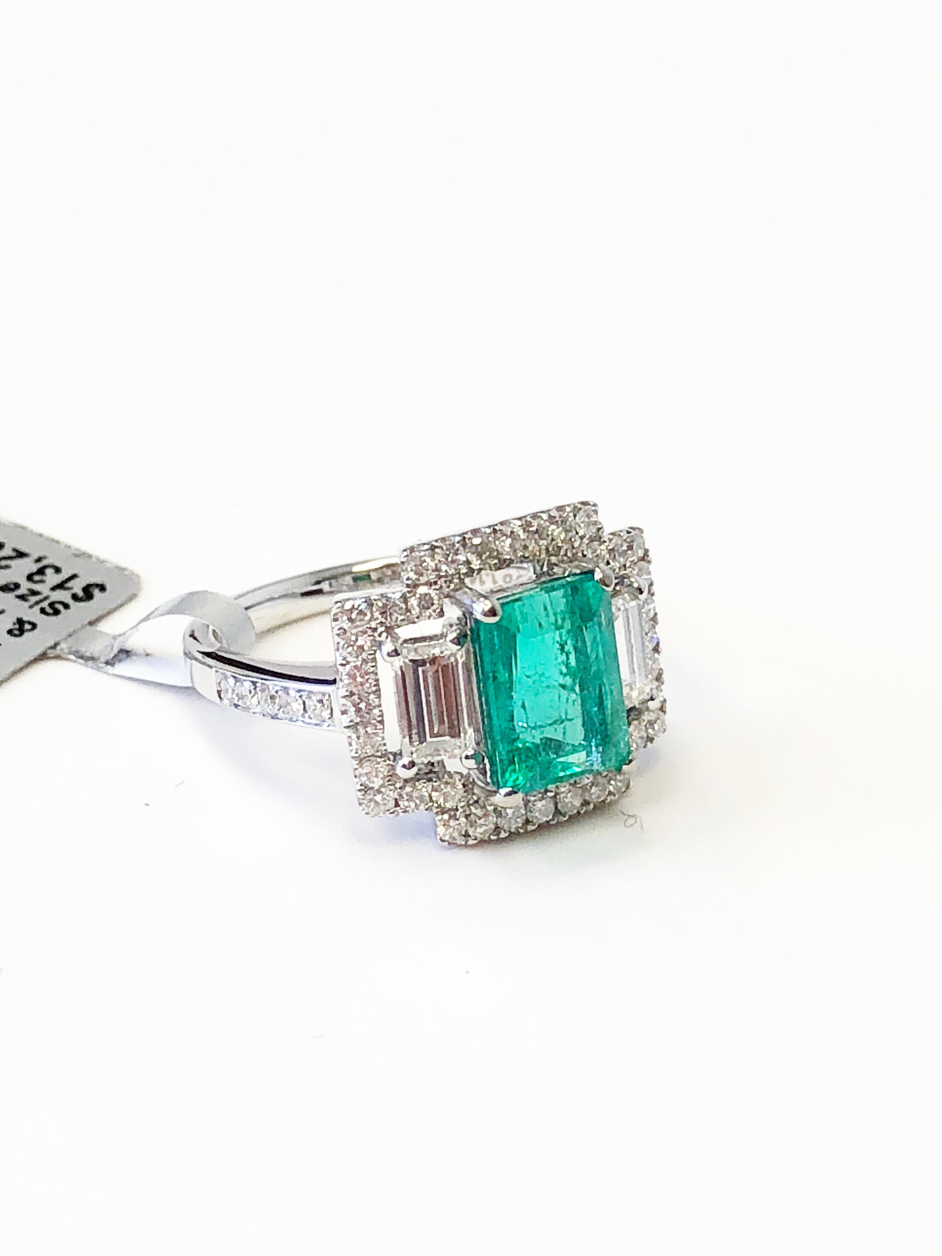 Bright emerald emerald cut weighing 2.05 carats surrounded by 1.14 carats of emerald cut and round diamonds in a handcrafted 18k white gold mounting.  Ring size is 6.  Beautiful addition to any jewelry collection.  Can be worn as a cocktail ring or
