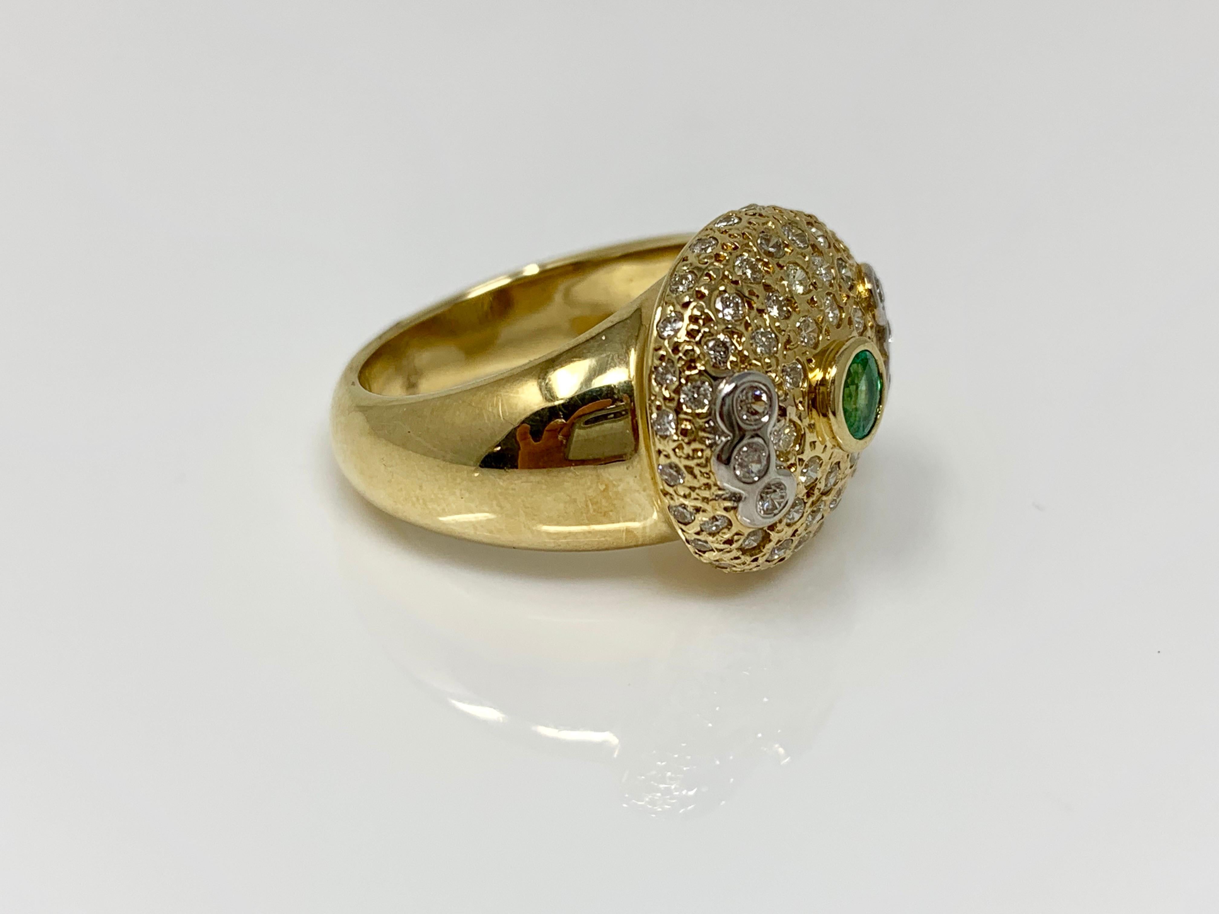 This attractive cocktail ring is handcrafted in yellow gold and features 0.25 carat emerald in the center and bezel set white diamonds weighing 0.76 carat with VS clarity and GH color  around it. The ring size is 5 1/2 and can be resized. 