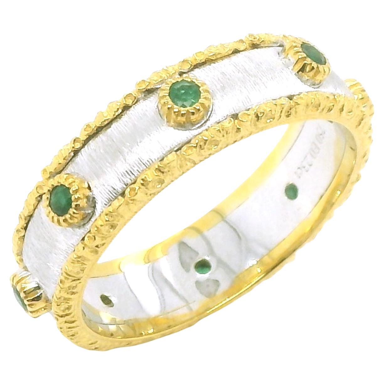 Cette magnifique bague présente des émeraudes d'un vert éclatant serties dans un anneau en or blanc et jaune 18 carats, avec une élégante combinaison de finitions appliquées à la main, inspirées de la Florentine. Les émeraudes sont serties
