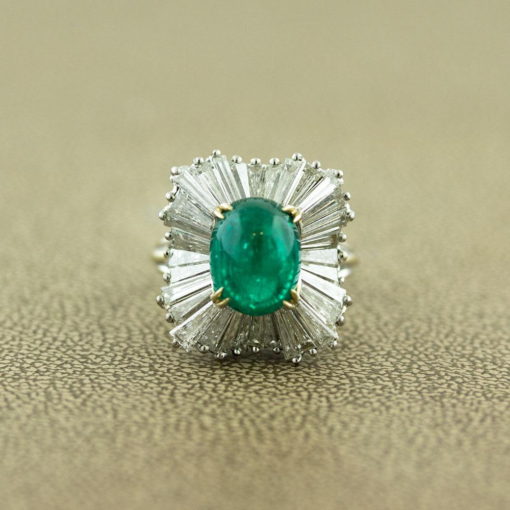 A luscious 5.83 carat cabochon emerald takes center stage of this ballerina style ring. It has a vivid green color and high luster that makes the stone glow! Surrounding the emerald are 2.70 carats of baguette cut diamonds set in a ballerina halo.