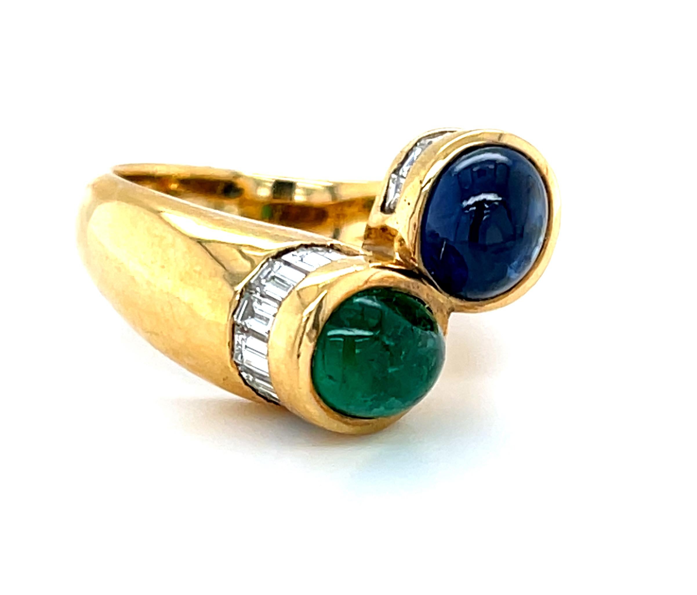 Questo splendido anello presenta un bellissimo zaffiro blu cabochon abbinato a uno smeraldo verde brillante con diamanti taglio baguette in oro giallo 18 carati. Lo zaffiro blu è quasi trasparente con un ricco colore blu medio, mentre lo smeraldo ha