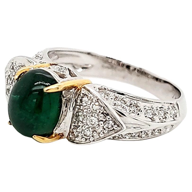 Emerald Cabochone ring with diamond studded gold planks. 

Yellow gold prongs hold this elegant emerald Cabochone neatly over a white gold enclosure and ring that is studded with white diamonds. 

The diamond studded gold wings add character and is
