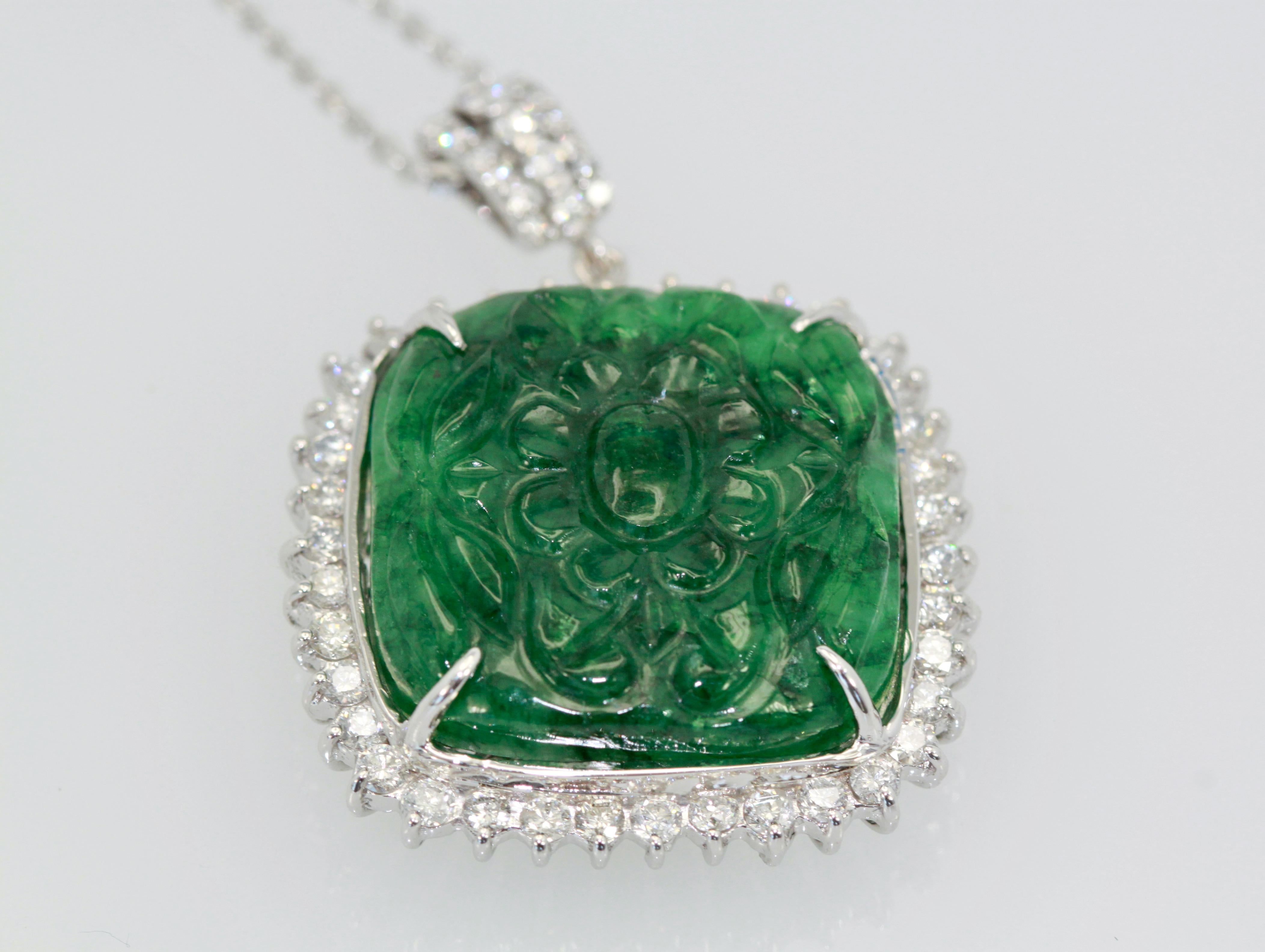 This gorgeous Emerald has a beautiful carved face of what seem to be flowers and is somewhat transparent.  The stone is 22.15 x 21.19 mm and weighs 16.9 grams.  It has a Diamond surround of round brilliant Diamonds G color and vs clarity which
