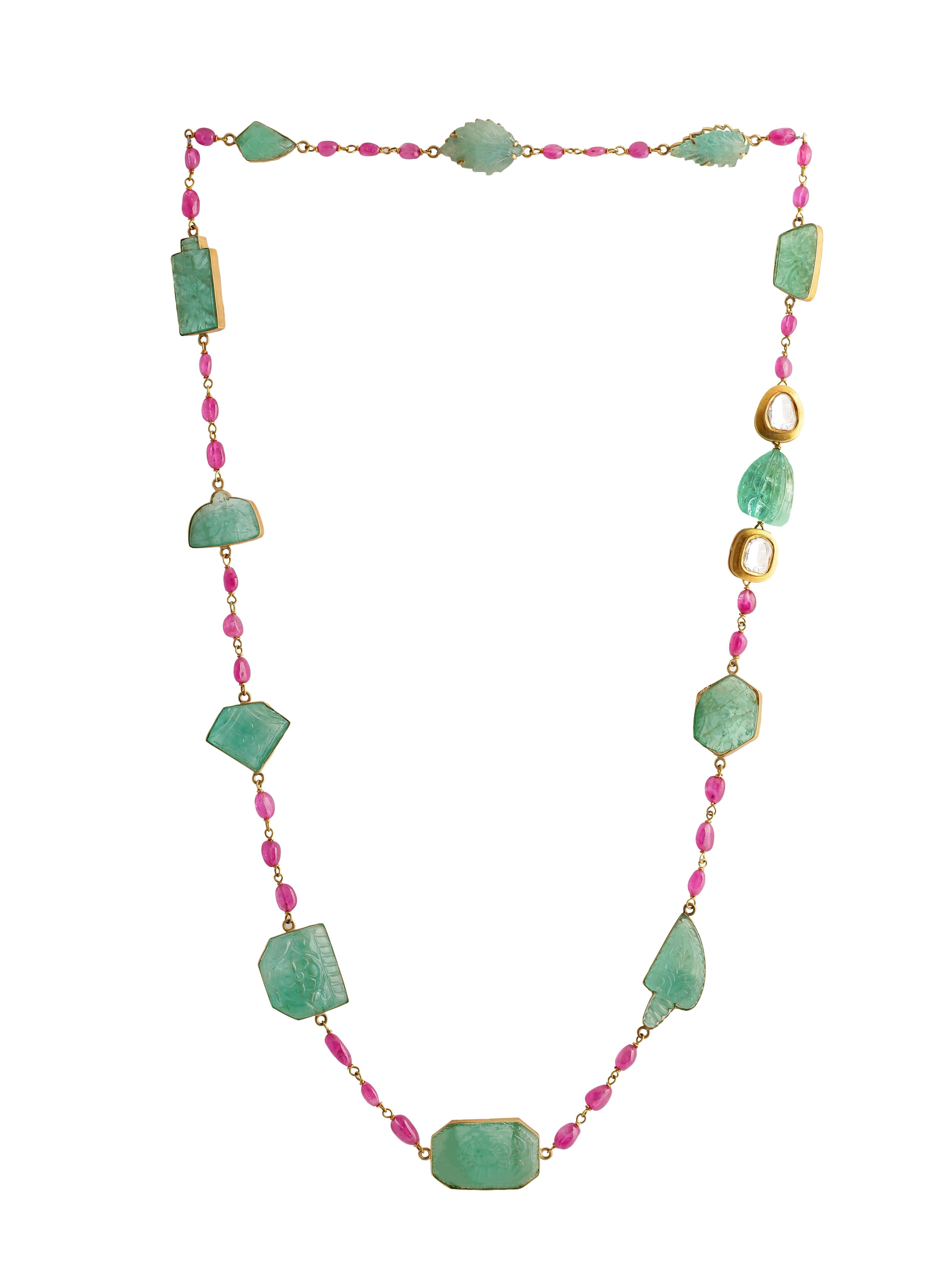 A beautiful necklace with Carved Colombian Natural Emeralds set in 18K Gold and strung with Rubies in a Gold wire. The Emeralds are all hand-carved each with a different carving inspired by the flora and Fauna around the state of Rajasthan. Carvings