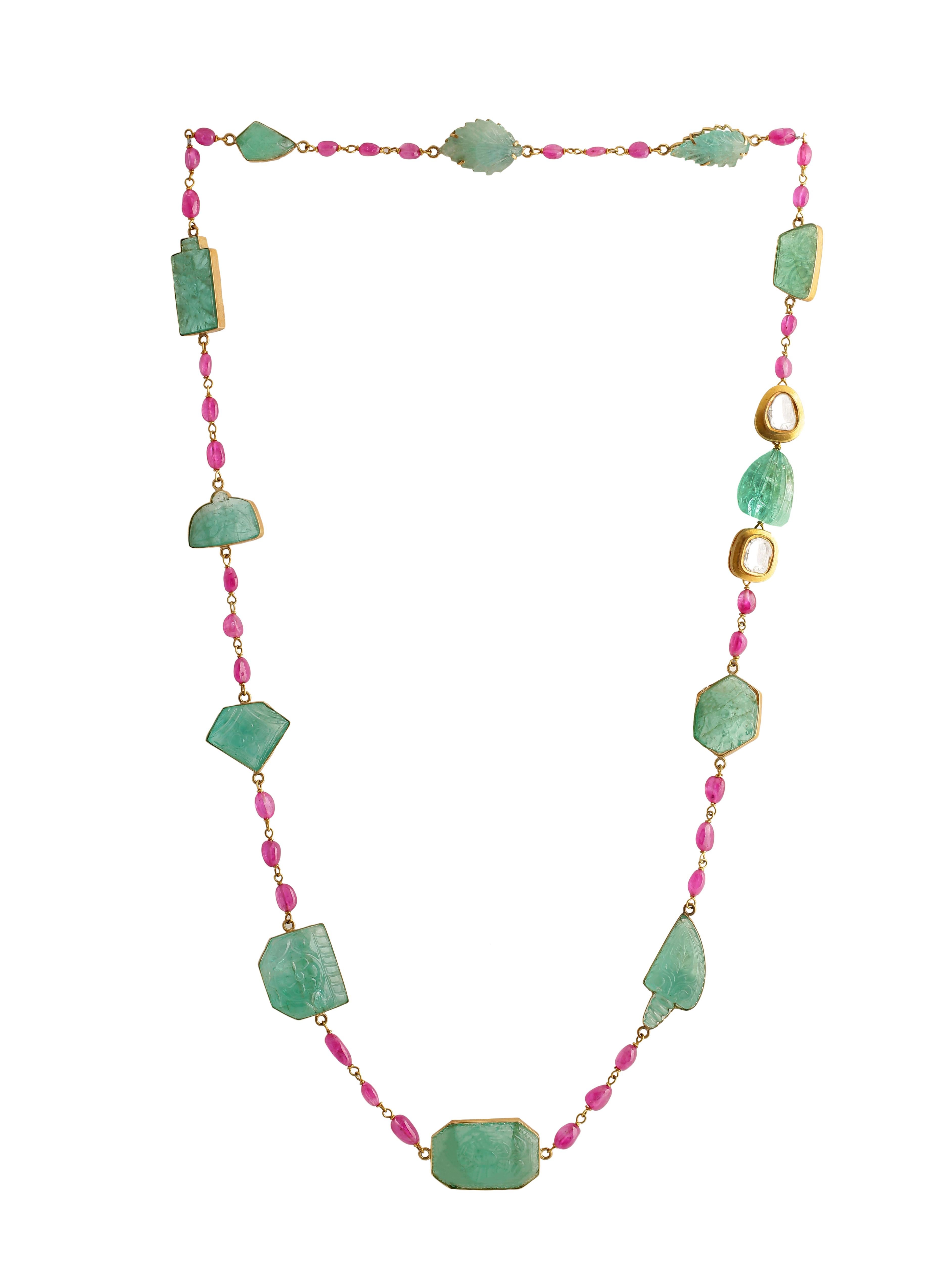 Un magnifique collier composé d'émeraudes naturelles de Colombie sculptées, serties dans de l'or 18 carats, et de rubis dans un fil d'or. Les émeraudes sont toutes sculptées à la main, chacune avec une sculpture différente inspirée par la flore et