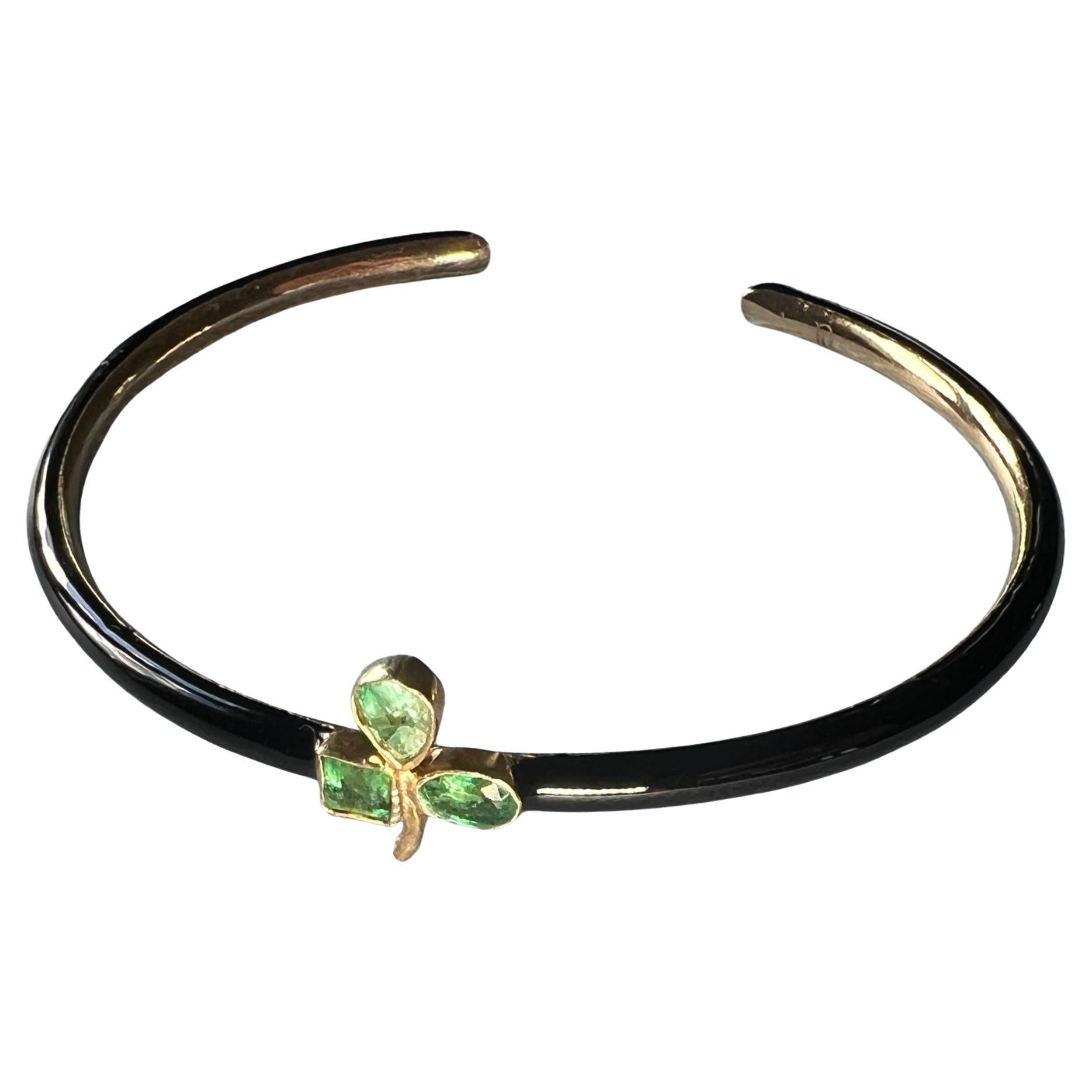 Emerald Clover Black Enamel Bracelet Bangle 

Designer J Dauphin

Gems: 3 Emeralds ( 2 Oval shaped and 1 squared )
Material: 14k Gold Plate with hand painted Black Enamel

Emeralds are valued for their purported healing properties. Traditionally,